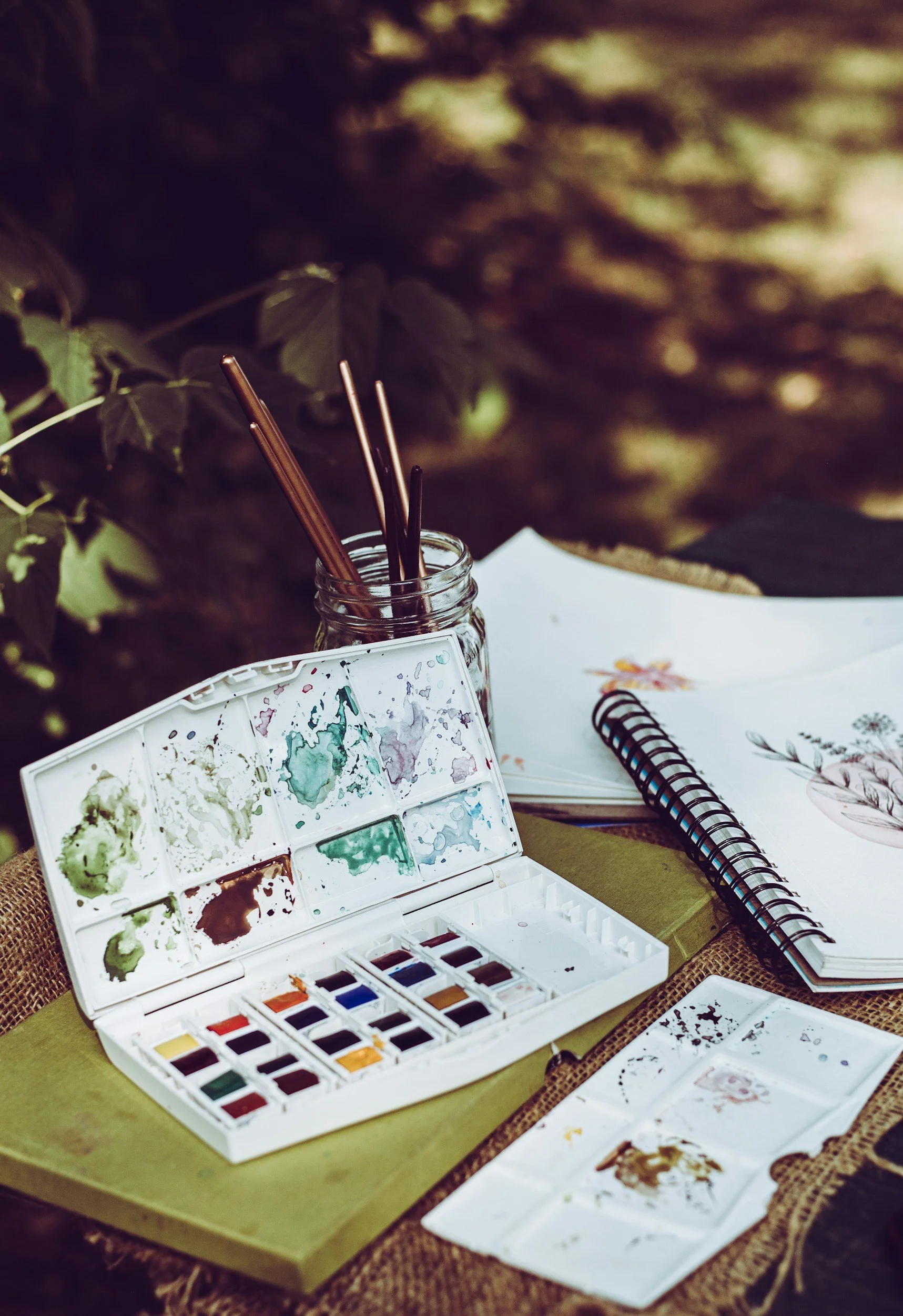 Watercolor paints and journaling materials used for creative self-care and restoration