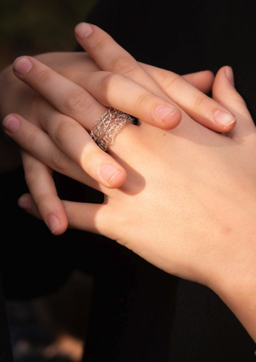 Mains de deux personnes qui se tiennent, l'une portant une bague en fil d'argent.