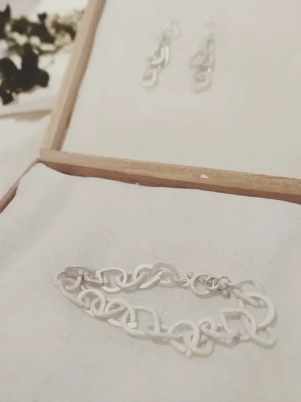 Un bracelet en plastique blanc placé sur une surface blanche, avec une image de tableau blanc en bois en arrière-plan.