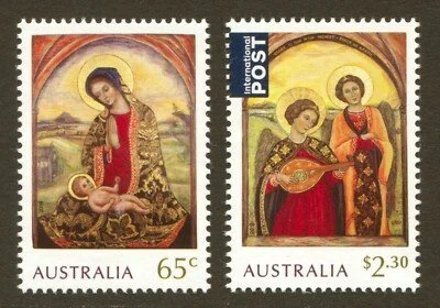 Two Australian postage stamps featuring religious artwork; the left stamp shows the Virgin Mary with baby Jesus, and the right stamp depicts two women, one playing a musical instrument.