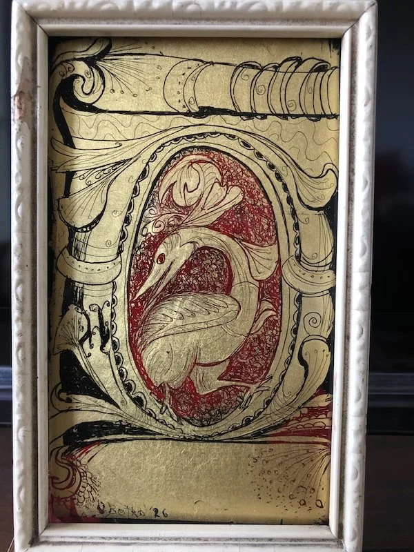 An ornate framed sketch of a heron within an oval, surrounded by elaborate, swirling decorative borders in black and red ink.