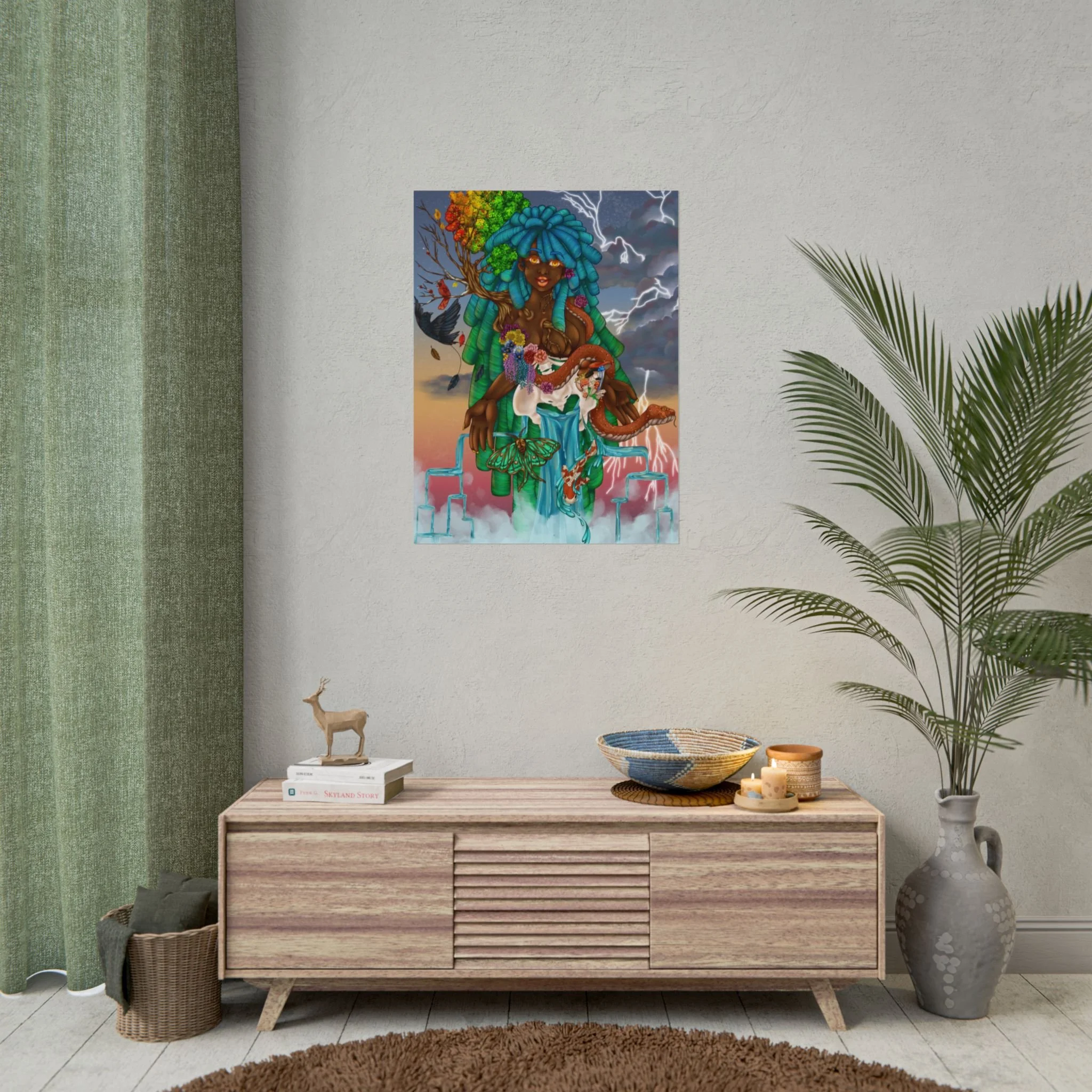 A wooden sideboard with horizontal slats, decorated with books, baskets, candles, and vases, against a white wall with colorful art of a woman with blue dreadlocks, a tree growing from her head, lightning in the background, set in a room with green c
