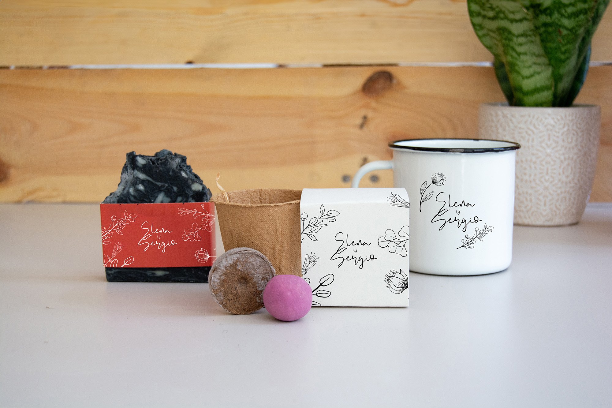 Un jabón de ceniza, un ecokit y una taza blanca con los nombres "Elena y Sergio", Con diseño de bodas.