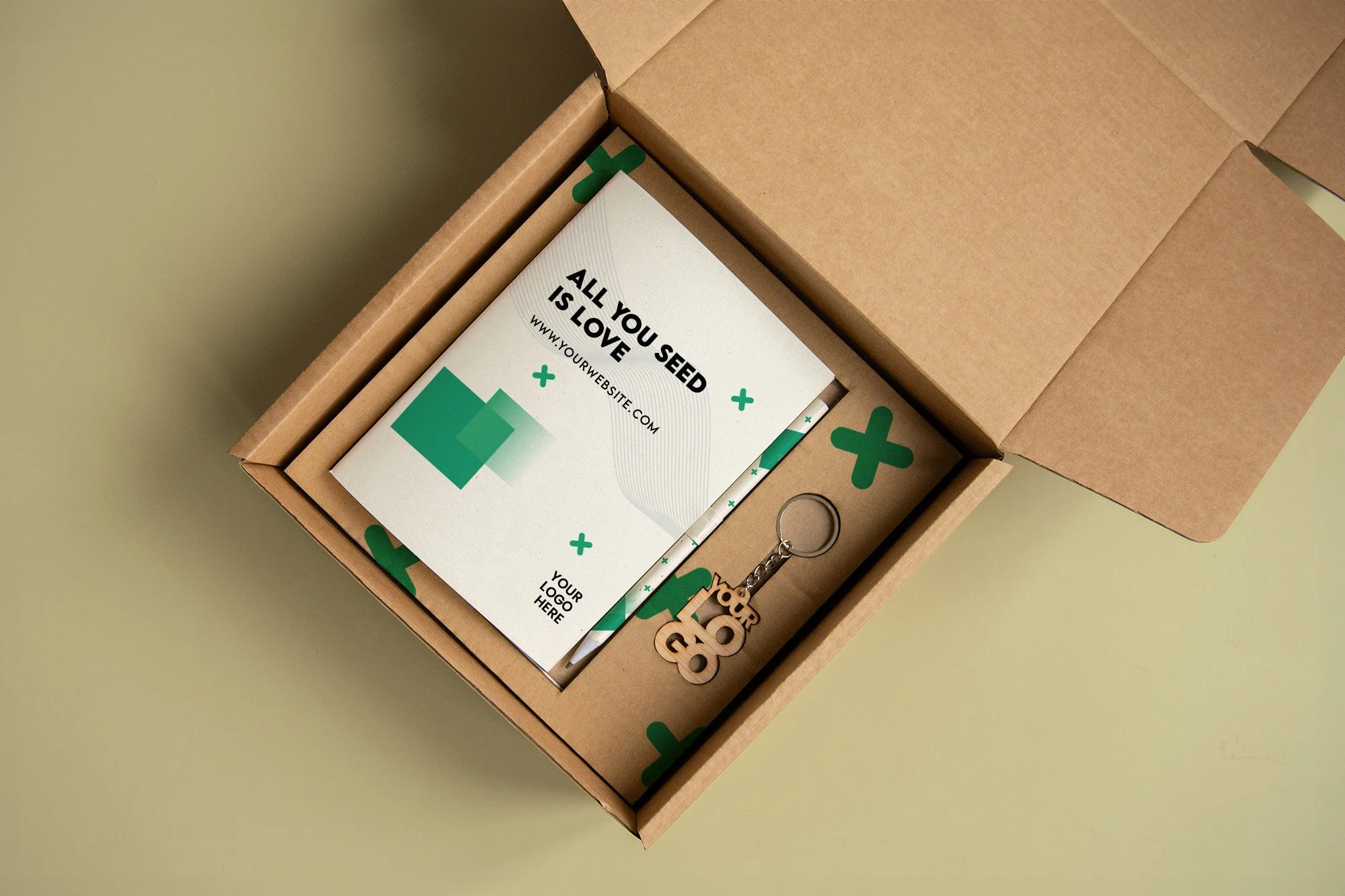 Caja de cartón con varios folletos, un llavero y un adorno de la palabra 'you' en madera, todo relacionado con la siembra y la jardinería, en un fondo de color verde claro.