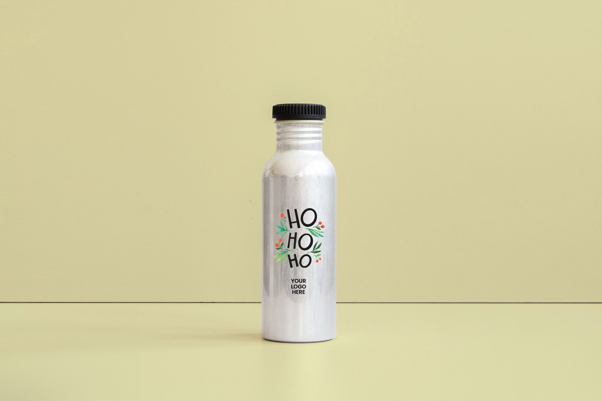 Botella blanca con etiqueta decorativa que dice "HO HO HO" en letras negras y un diseño de hojas verdes y pequeñas bayas naranjas. La botella tiene una tapa negra y un espacio para logotipo en la parte inferior. Fondo de color beige claro.