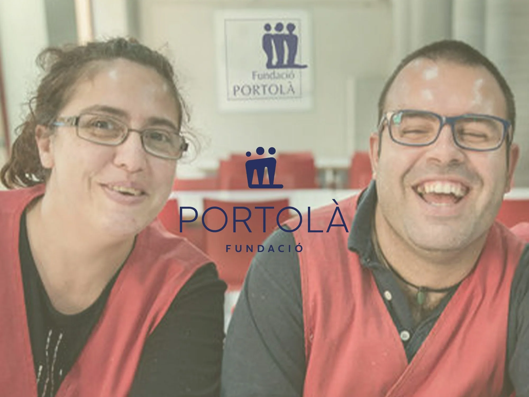 Dos personas con gafas y ropa roja, sonriendo, en un fondo con logotipo de la fundación Portolà y un cartel con tres figuras humanas en azul.