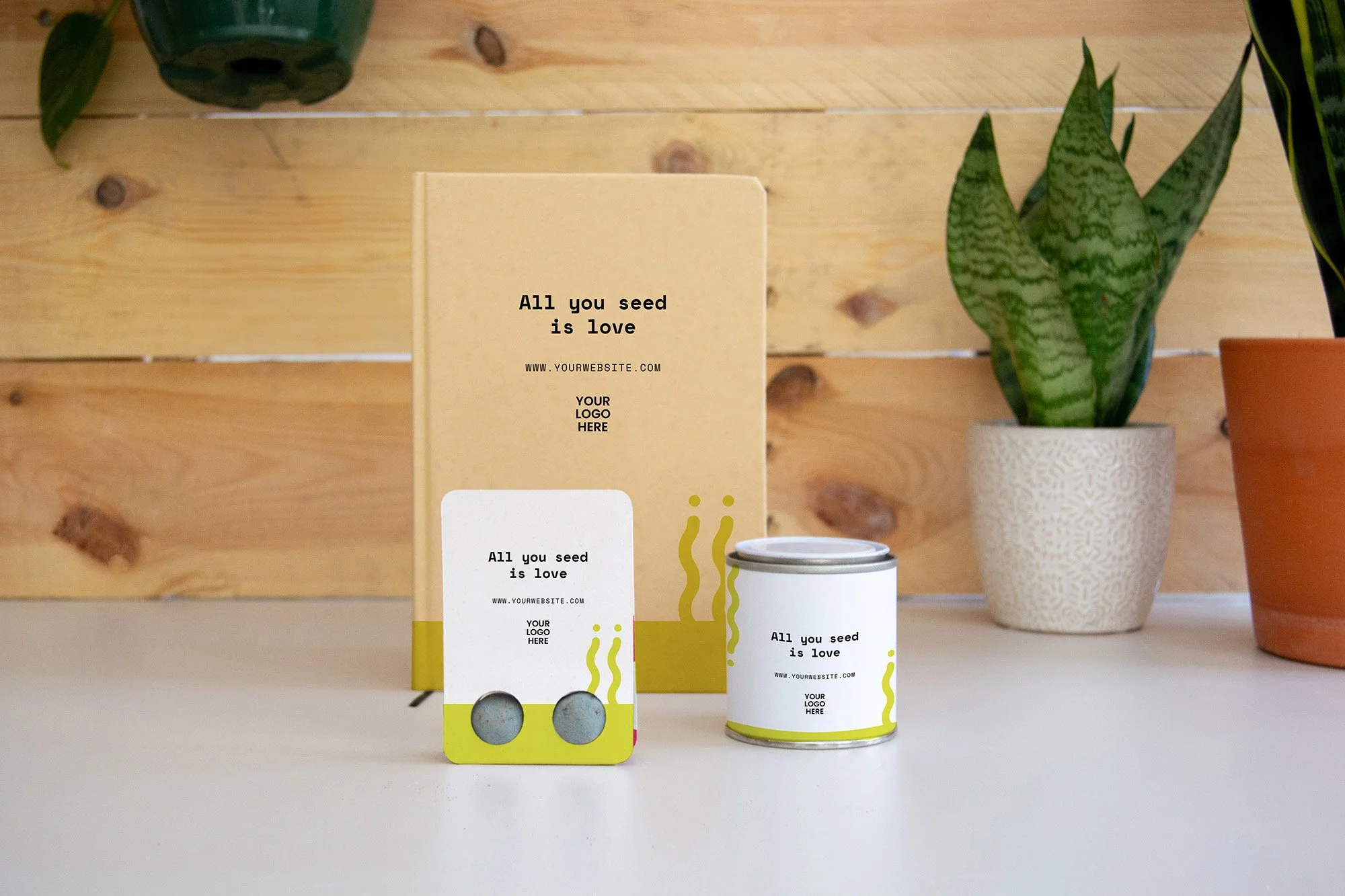 Varios envases y una caja de cartón con la frase "All you seed is love" en un fondo de paredes de madera y plantas en macetas.