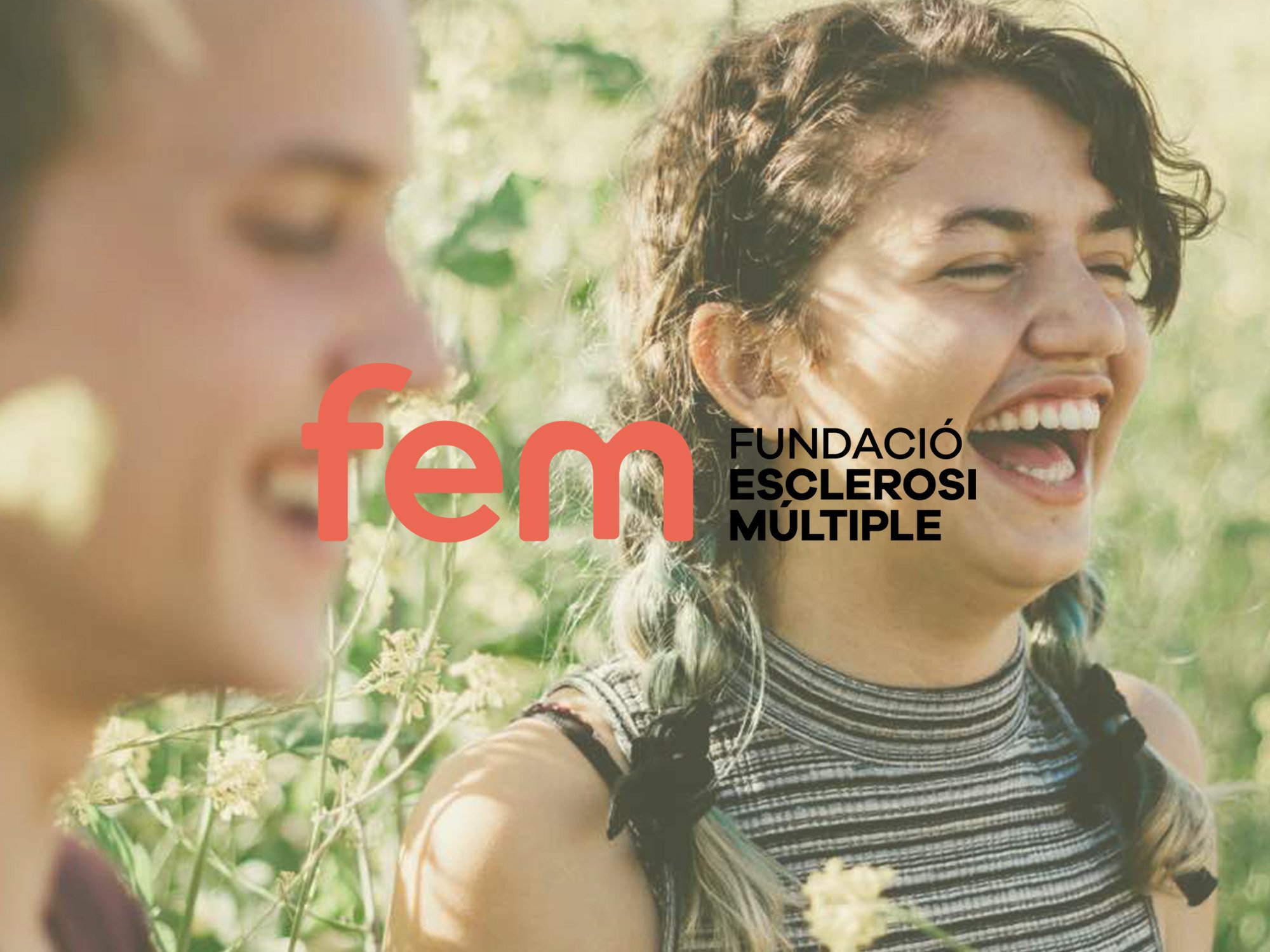 Jóvenes sonriendo y disfrutando en un campo de flores, con el logo de la Fundación Esclerosi Múltiple en el fondo.