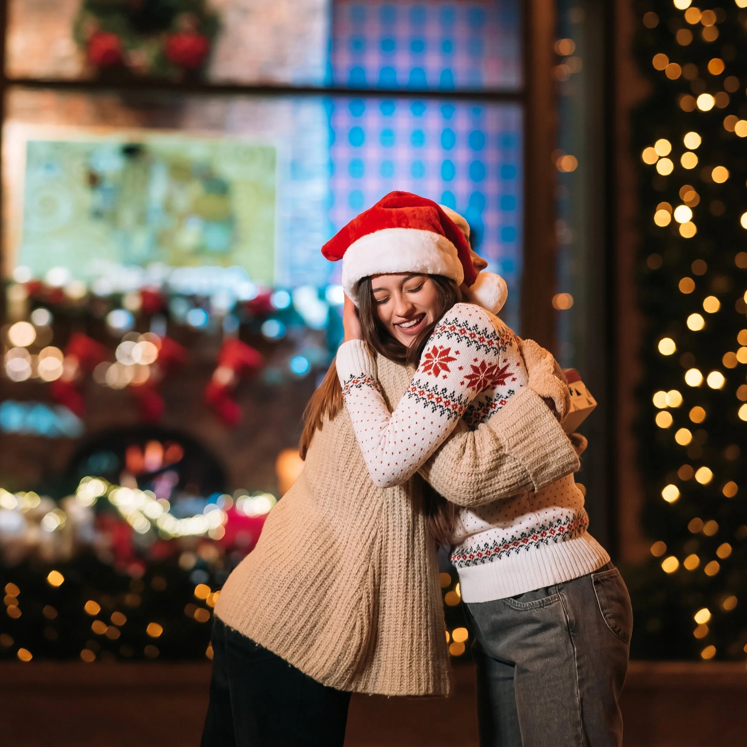 Una pareja feliz celebrando Navidad con un abrazo en una sala decorada con luces y adornos navideños, usando gorros de Santa