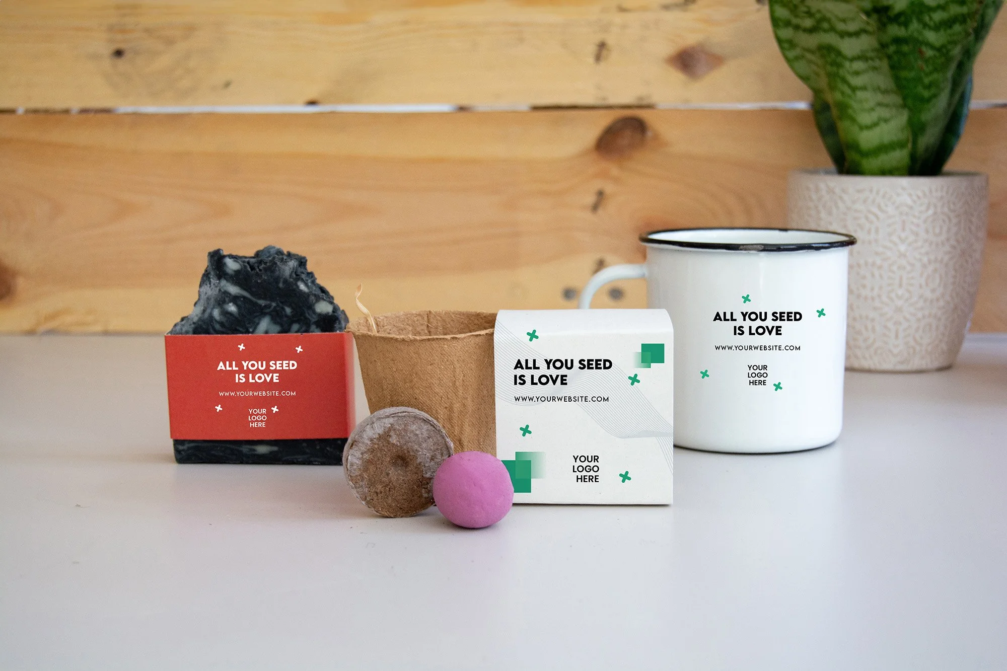 Conjunto de objetos sobre una mesa de madera: un jabón de ceniza, una taza blanca y un ecokit. Todo personalizado con un diseño de empresa.