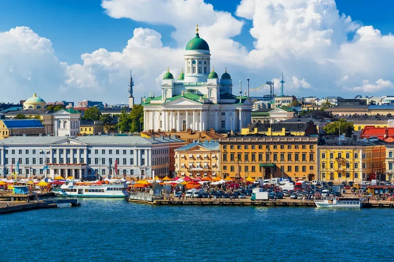 Kuva Helsingin matkustajasatamasta, jossa näkyy kalasatama ja Tuomiokirkko taustalla, veneitä vesistössä ja värikkäitä rakennuksia.
