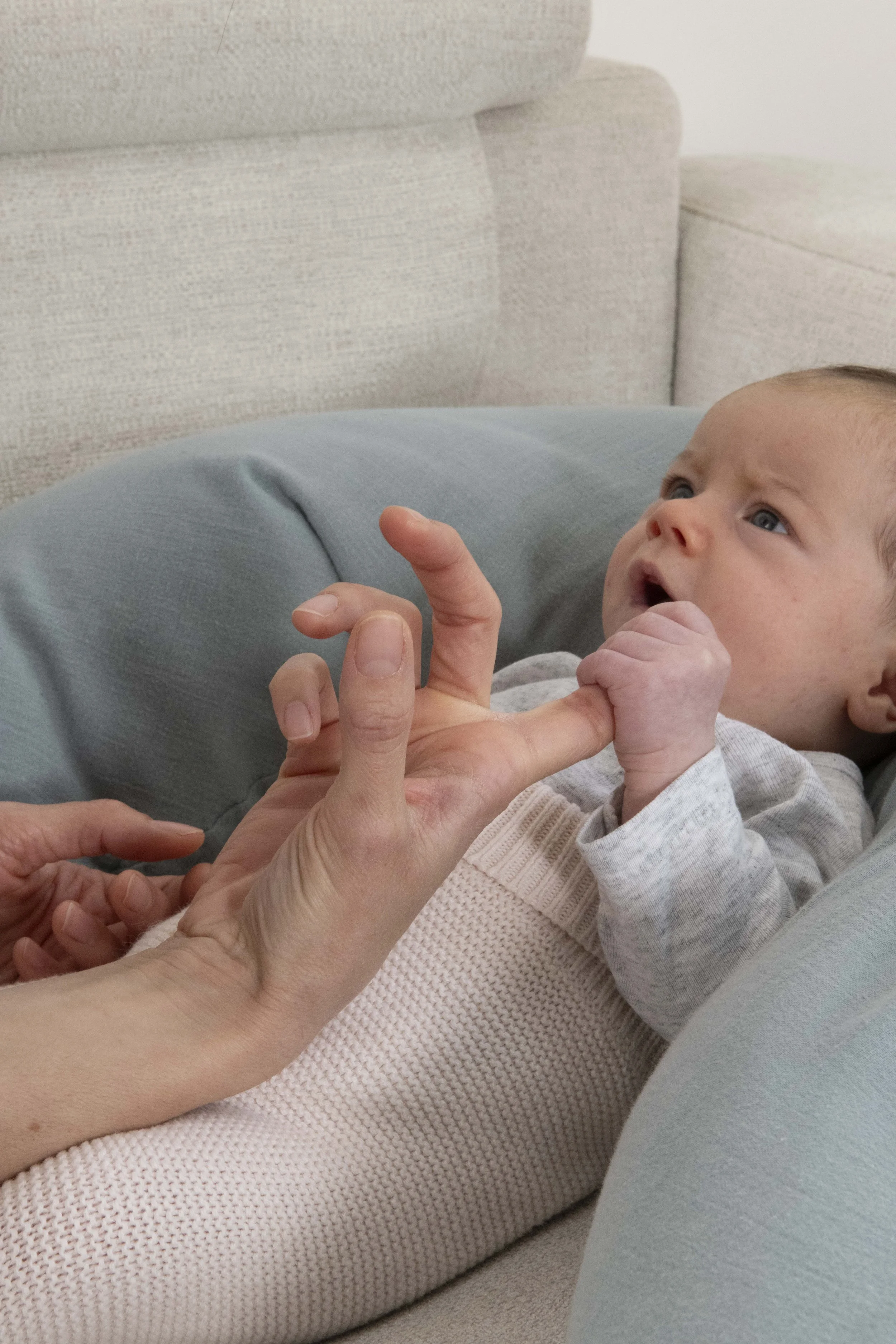 Un bébé regarde attentivement un adulte qui lui tend la main.