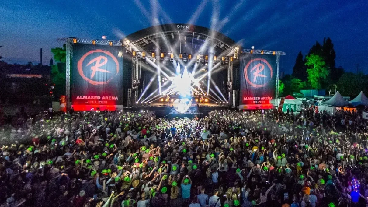 Crowd at a concert or festival with stage lighting and large screens at Almased Arena in Uelzen, Germany.