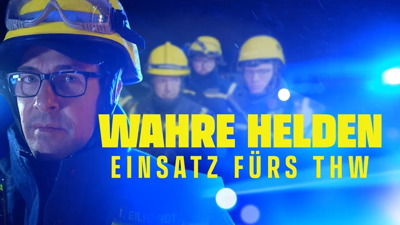 Emergency responders in helmets and uniforms at night with flashing blue lights and rain, featuring bold yellow text that reads "Wahre Helden Einsatz fürs THW."
