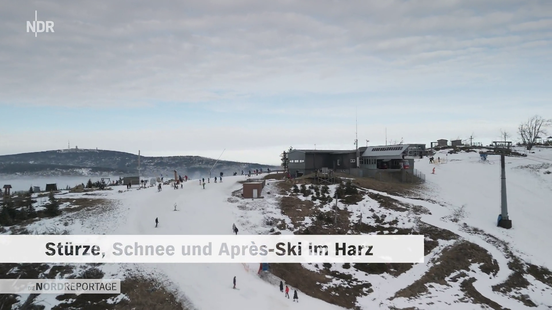 Snow-covered mountain landscape with people skiing and hiking, ski lift on the right, and a building at the top of the slope.