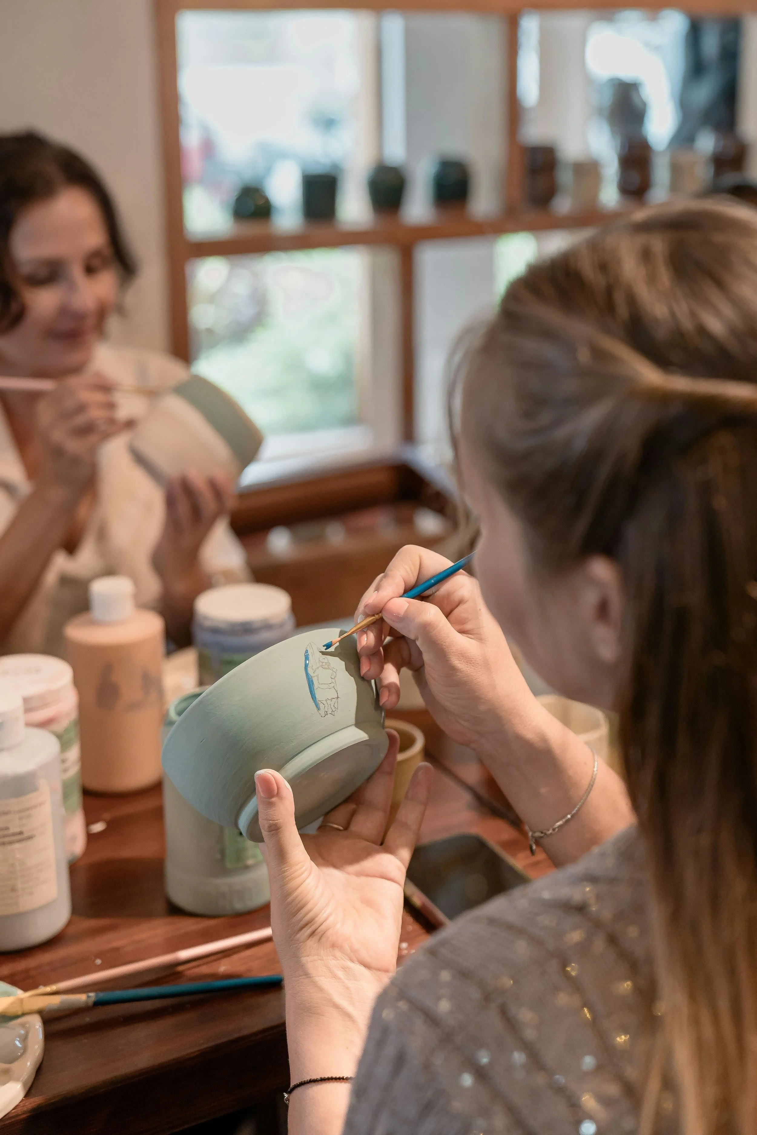 People painting ceramic mugs at a workshop.