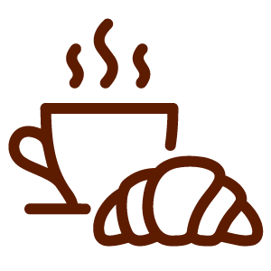 A steaming cup of coffee with a croissant.