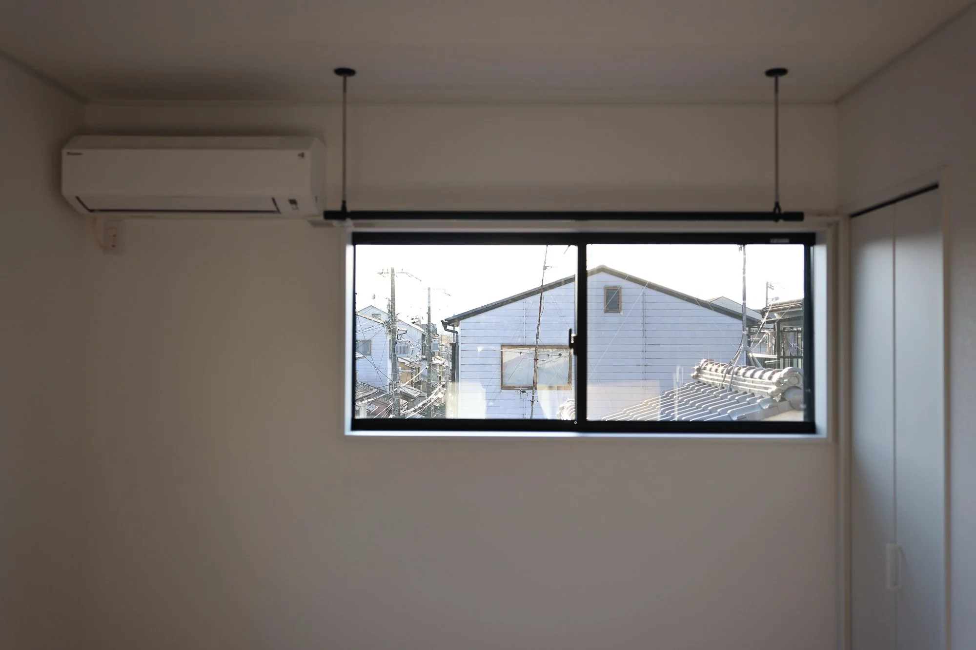 View of neighboring houses and power lines outside a window from inside a room.