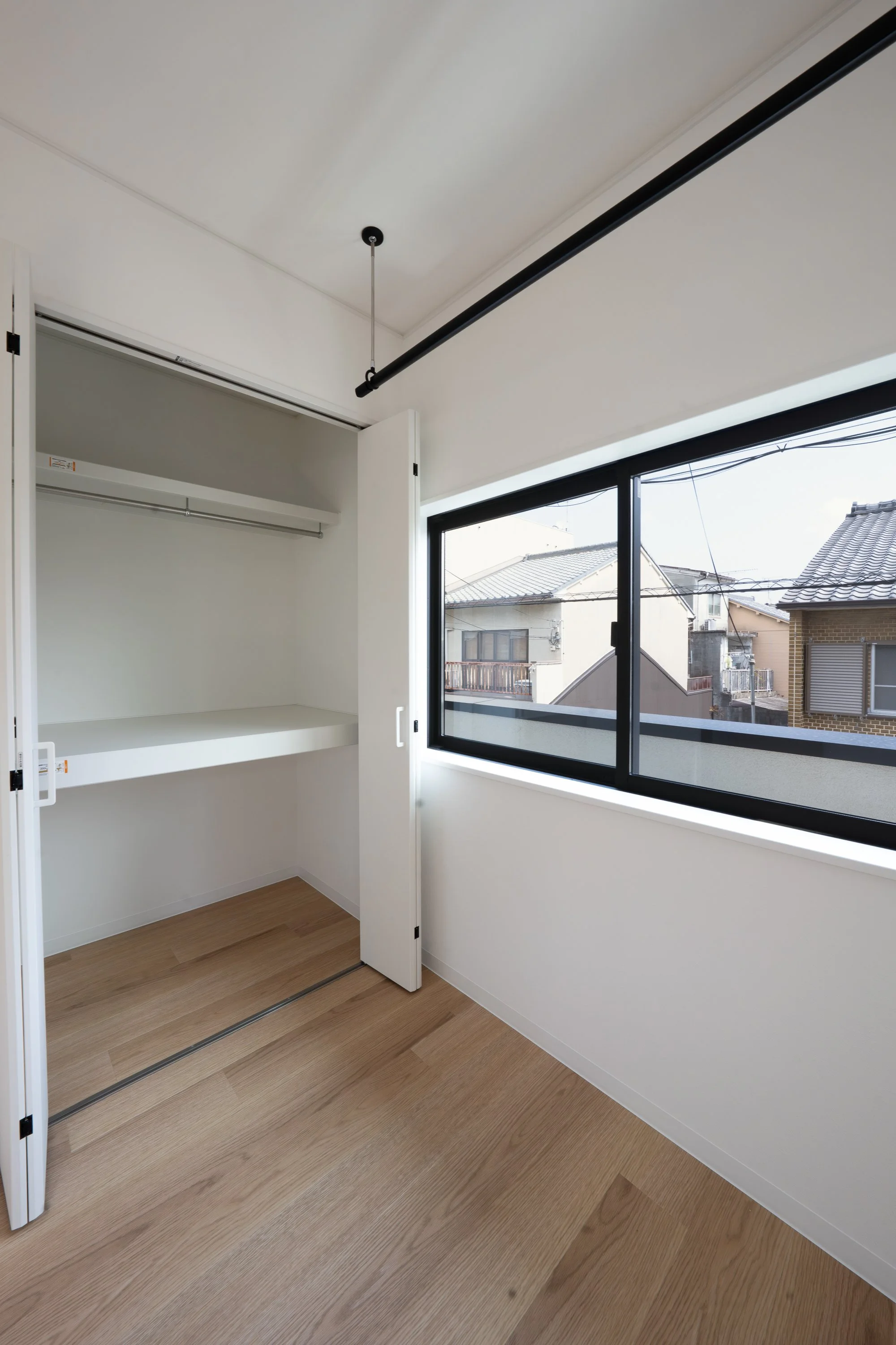 Empty room with a closet, large window, and wooden floor.