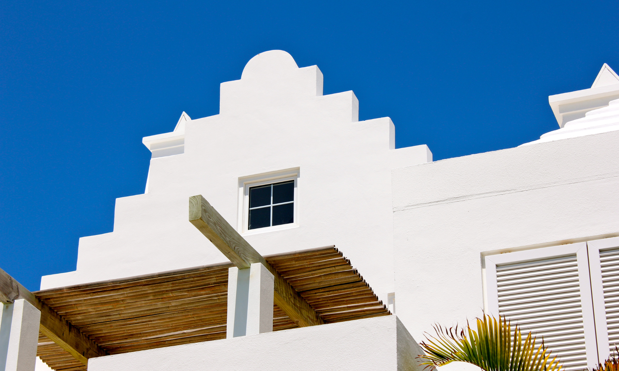White Bermuda building with stepped roof under clear blue sky, reflecting local architecture