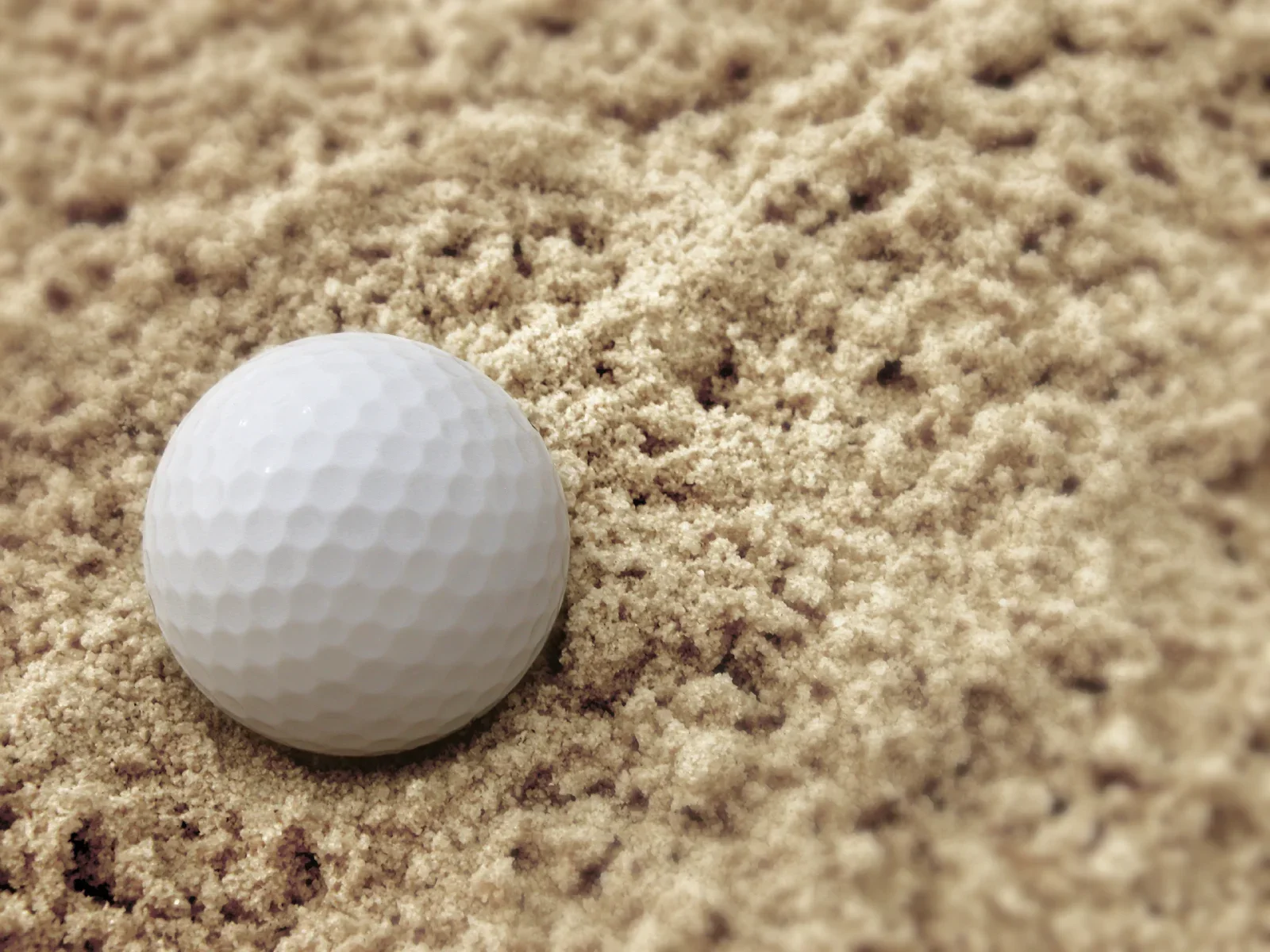 Eine Golfkugel liegt auf Sand, der an einem Golfplatz verwendet wird.