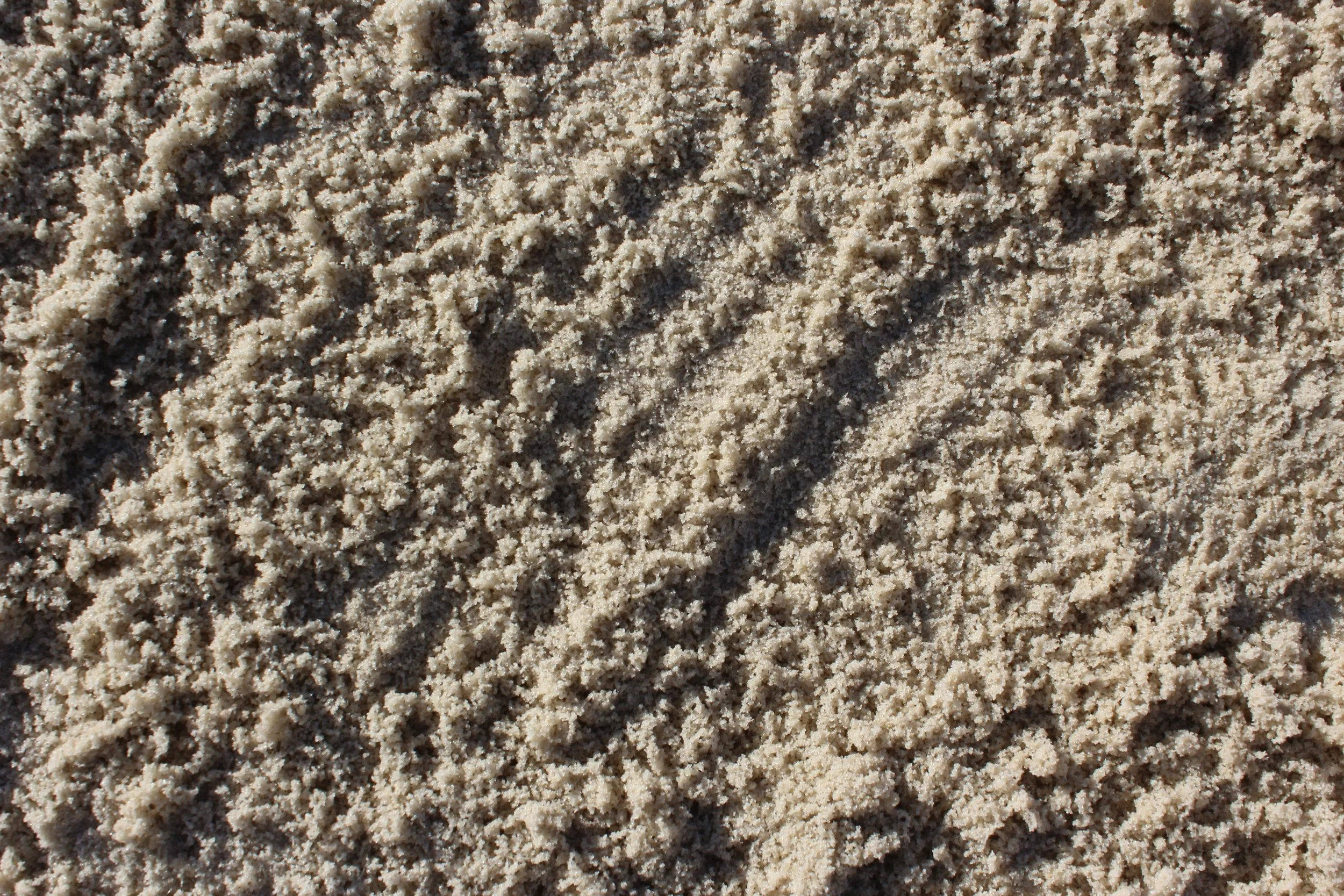 Nahaufnahme von feinem Sand mit kleinen Körnern und Strukturen.