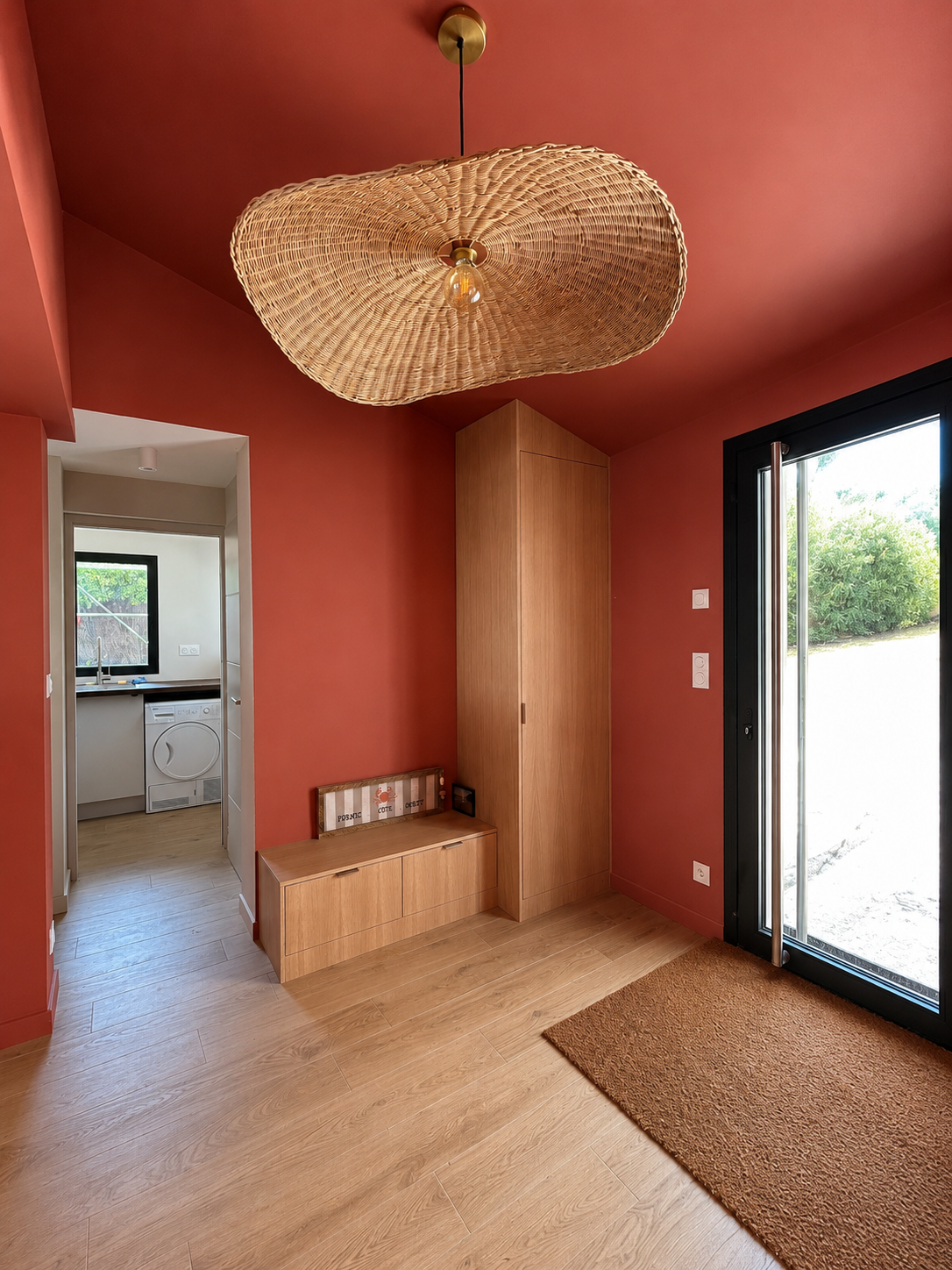 Cette entrée affirme son caractère grâce à une teinte terracotta chaleureuse qui met en valeur les éléments en bois. La peinture crée une atmosphère accueillante et élégante, sublimée par la lumière naturelle.