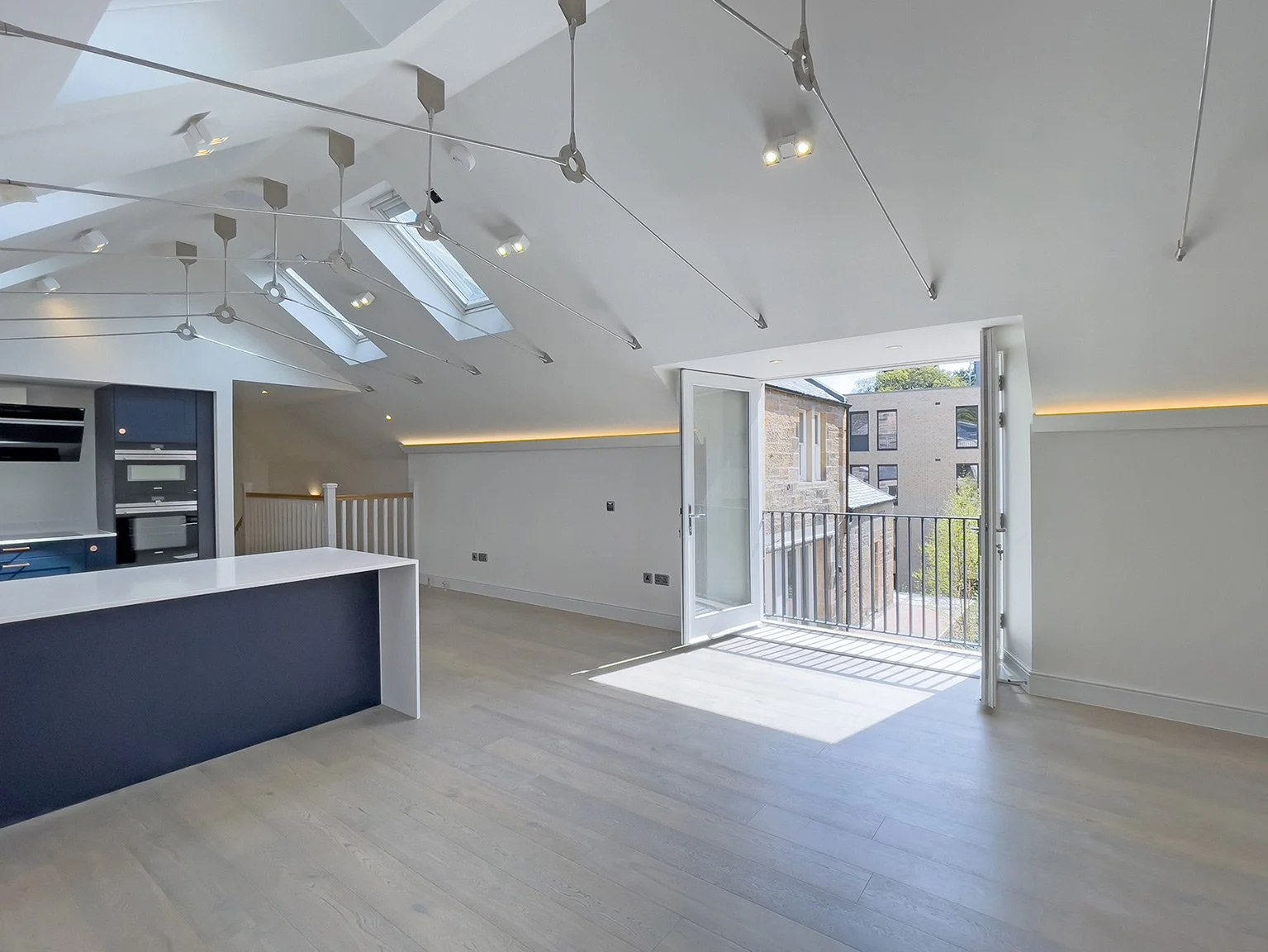 Bright, modern apartment interior with skylights, a door leading to a balcony, and an open living space.