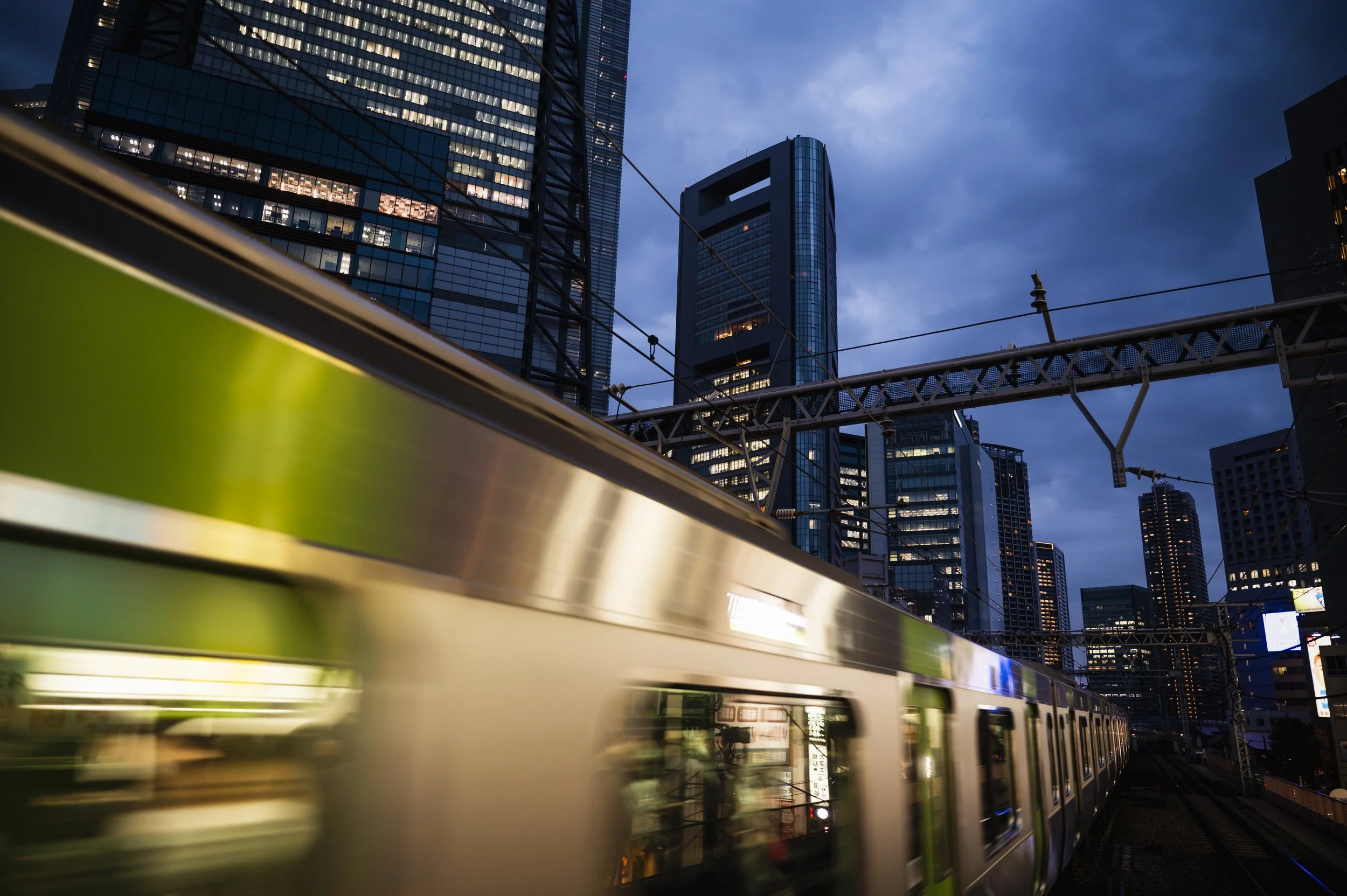 Yamanote Line train passing Tokyo skyscrapers at dusk — Japan transport guide