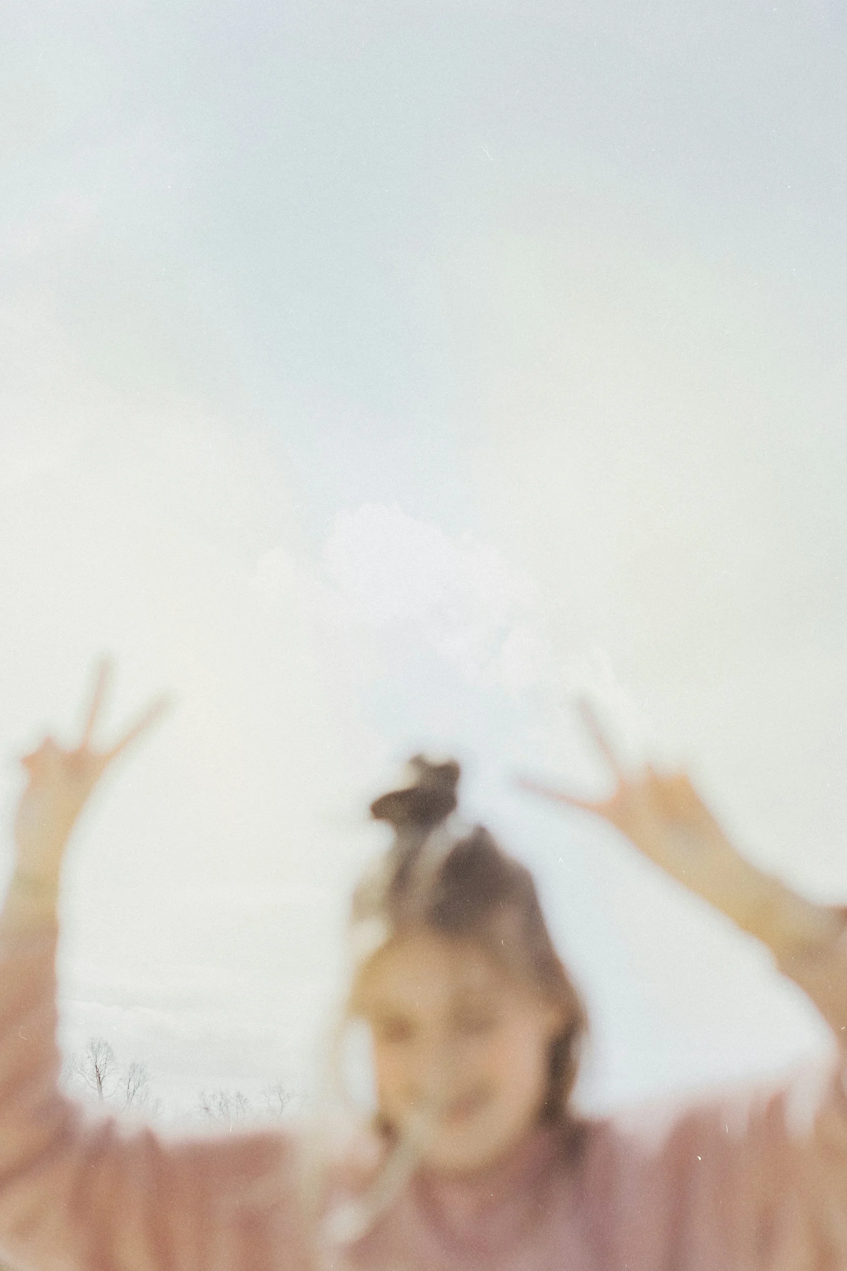 Child looking through a translucent surface with hands pressed against it, creating a silhouette effect.