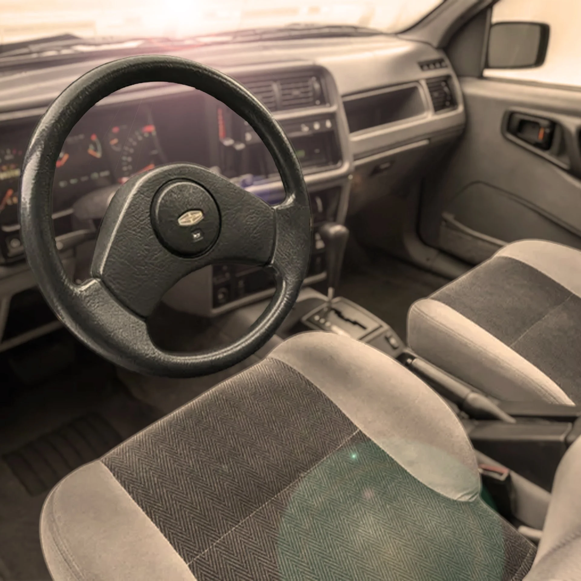 Interior of a vehicle showing the steering wheel, dashboard, gear shift, and front seats.