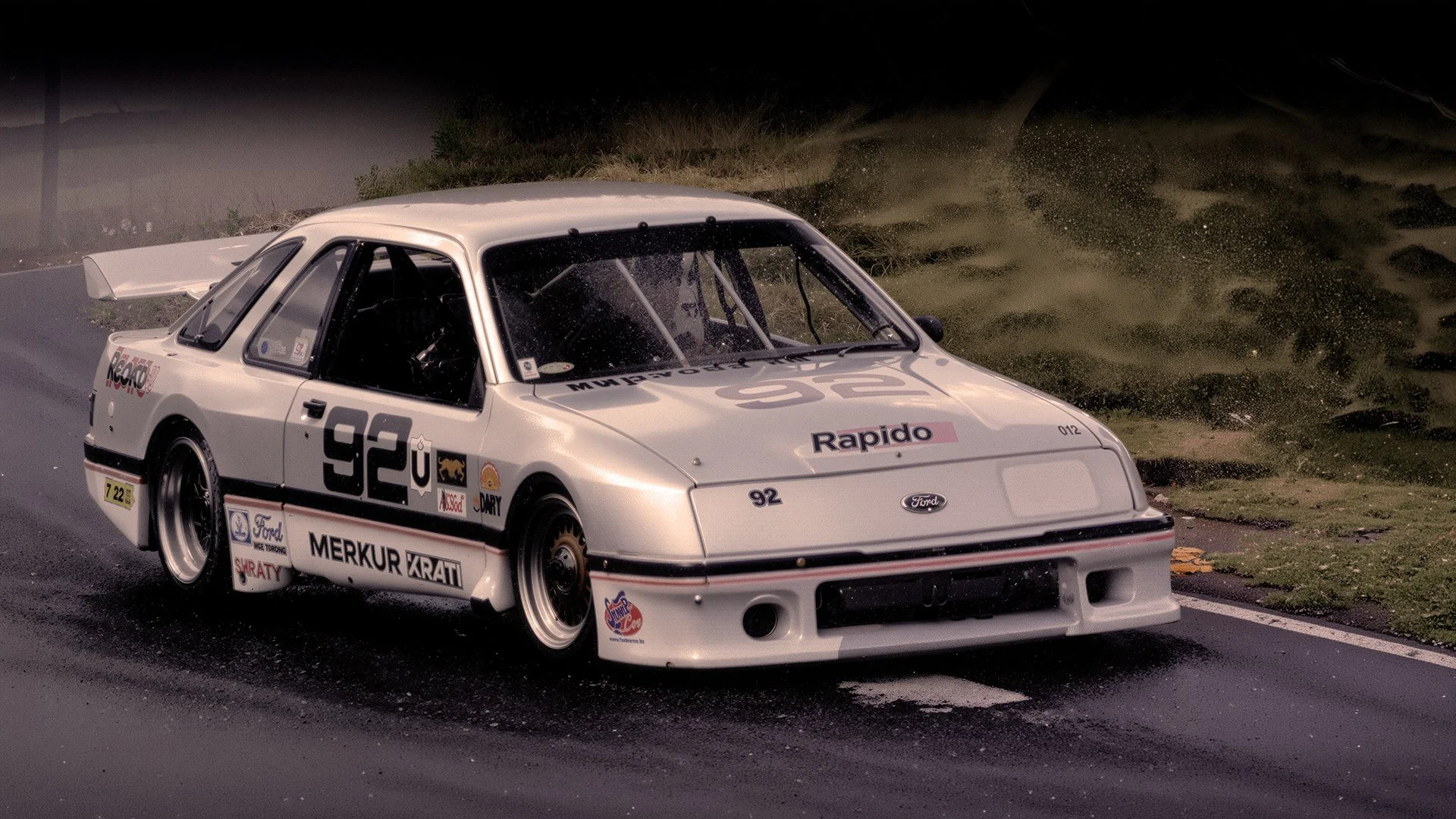 A white race car with number 92 and various sponsor logos, racing on a wet road at night.