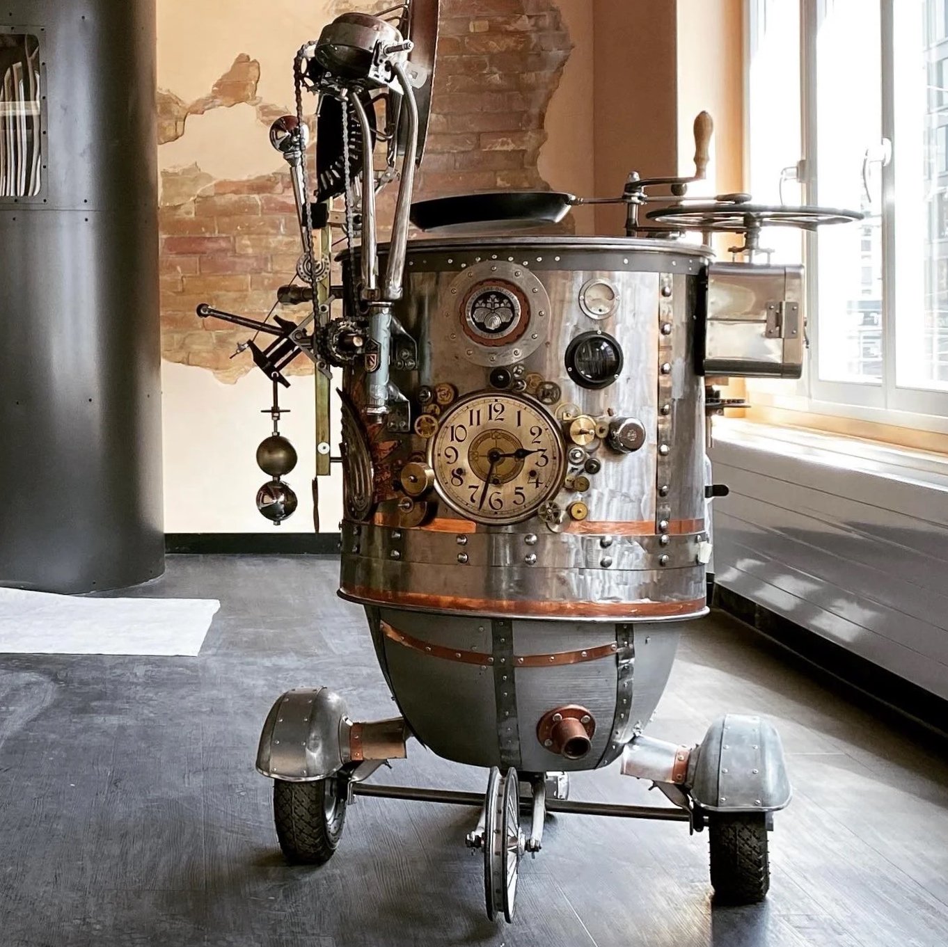 Steampunk robot with clock face, gauges, and mechanical parts on wheels, near a window in a room with brick and painted walls.