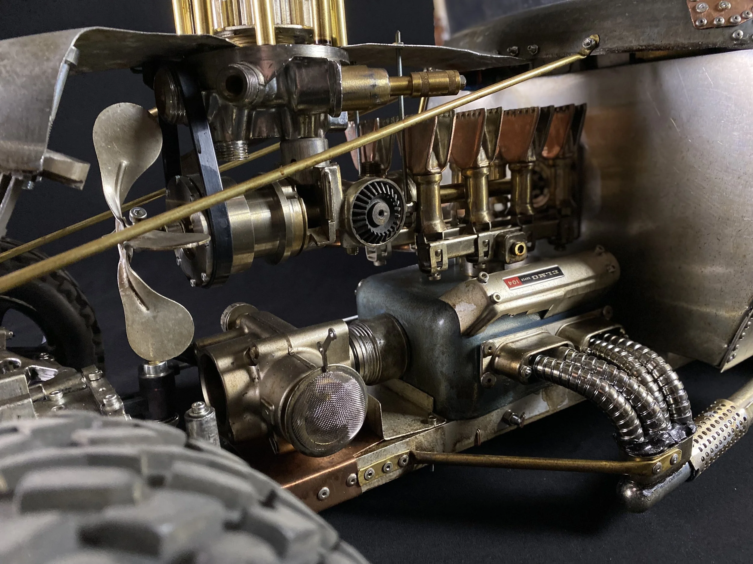 Close-up of a vintage racing car engine with intricate metal components, tubes, and gears.