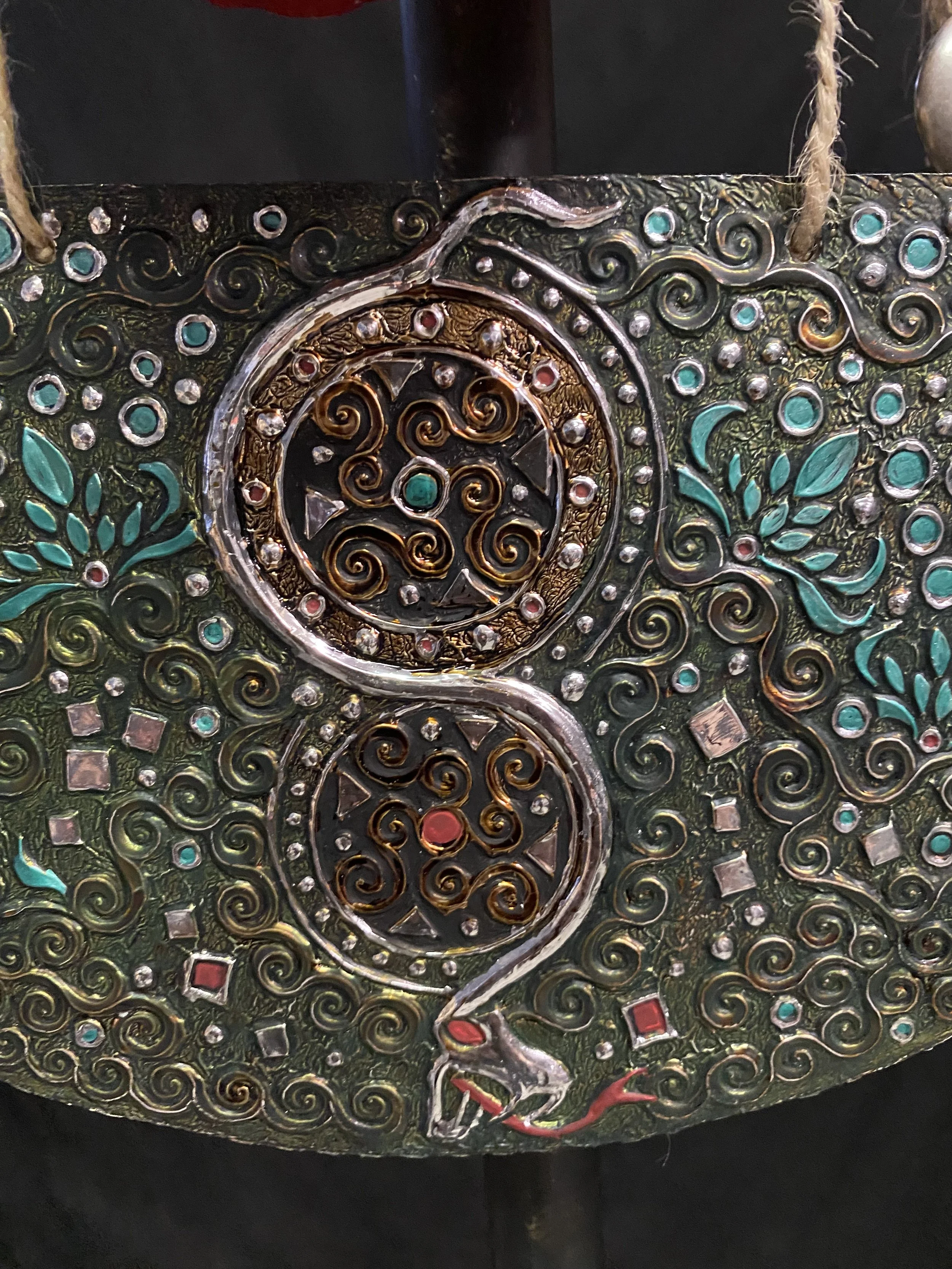 Decorative metal purse with swirling patterns, colored stones, and a dragon motif.