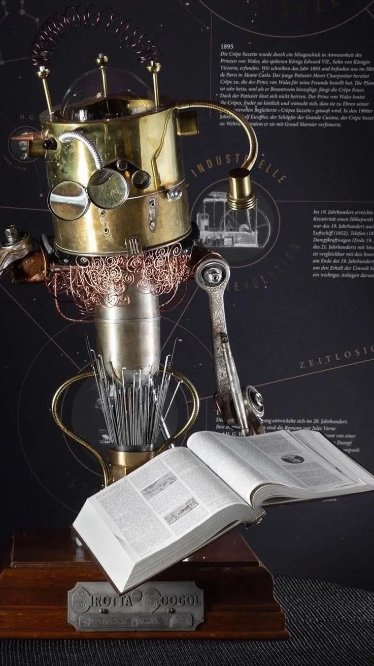 A steampunk sculpture resembling a robot head, made of metal parts, with an open book on a wooden base in front.