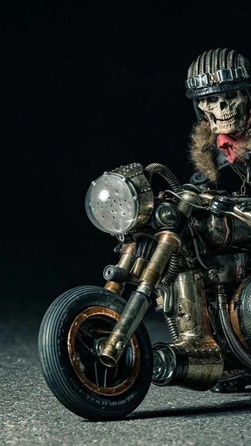 A skeleton wearing a helmet and red bandana riding a custom motorcycle against a black background.