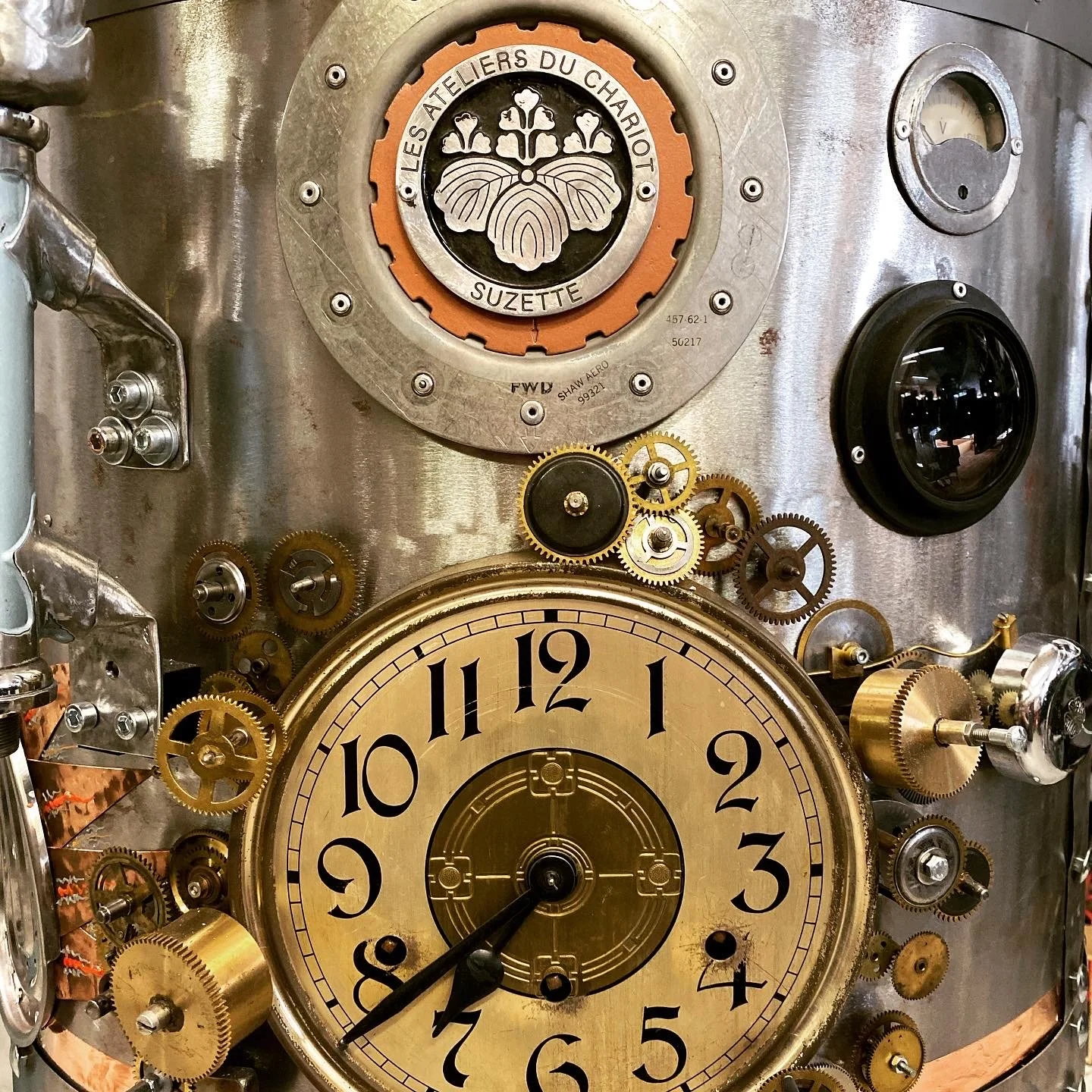 A close-up of a vintage clock with an intricate mechanical design, featuring visible gears, dials, and a large central clock face.