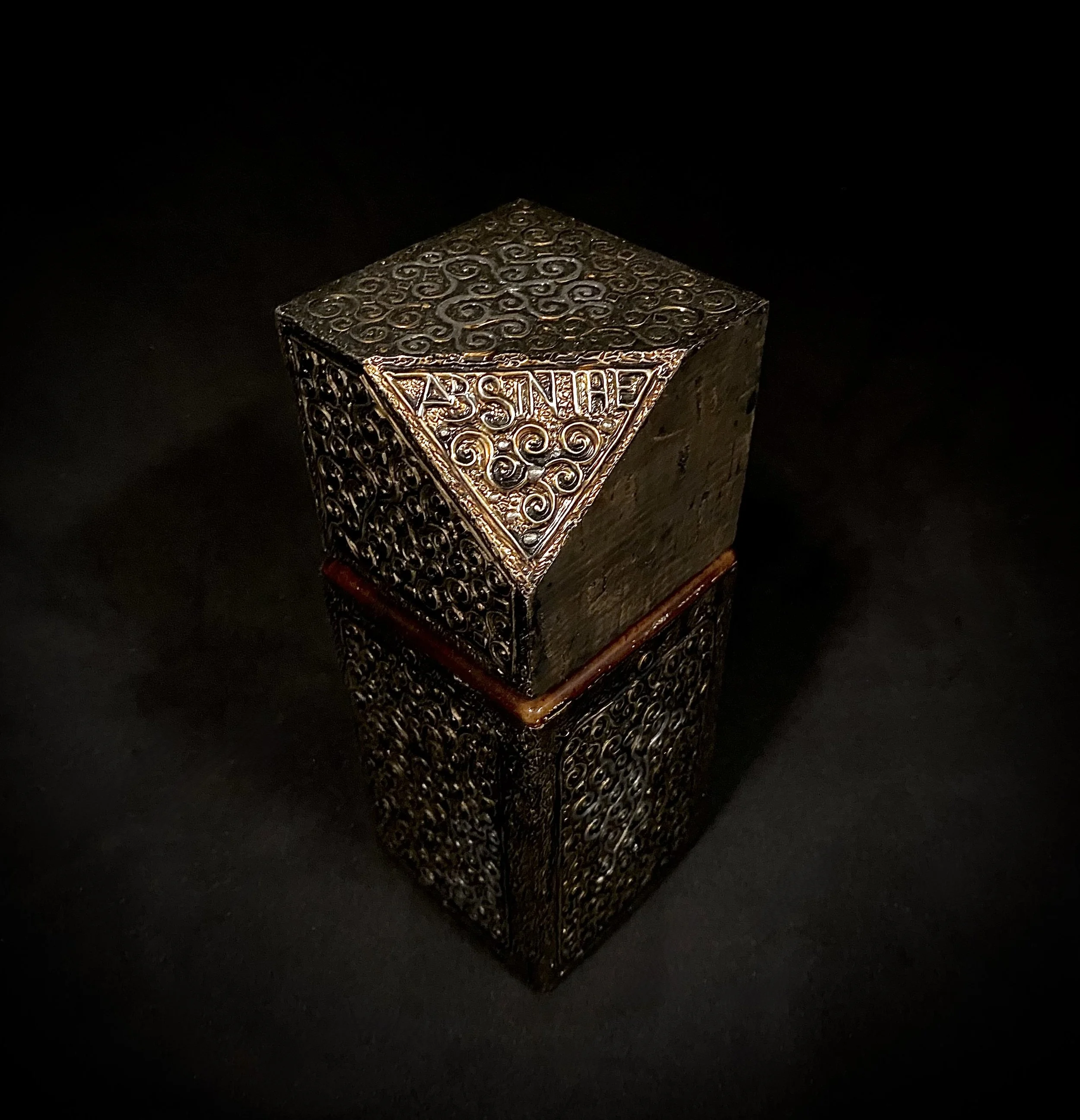 A decorative metal box with intricate swirling patterns, labeled with the word "PASSNIE" on the top surface, resting on a dark surface.