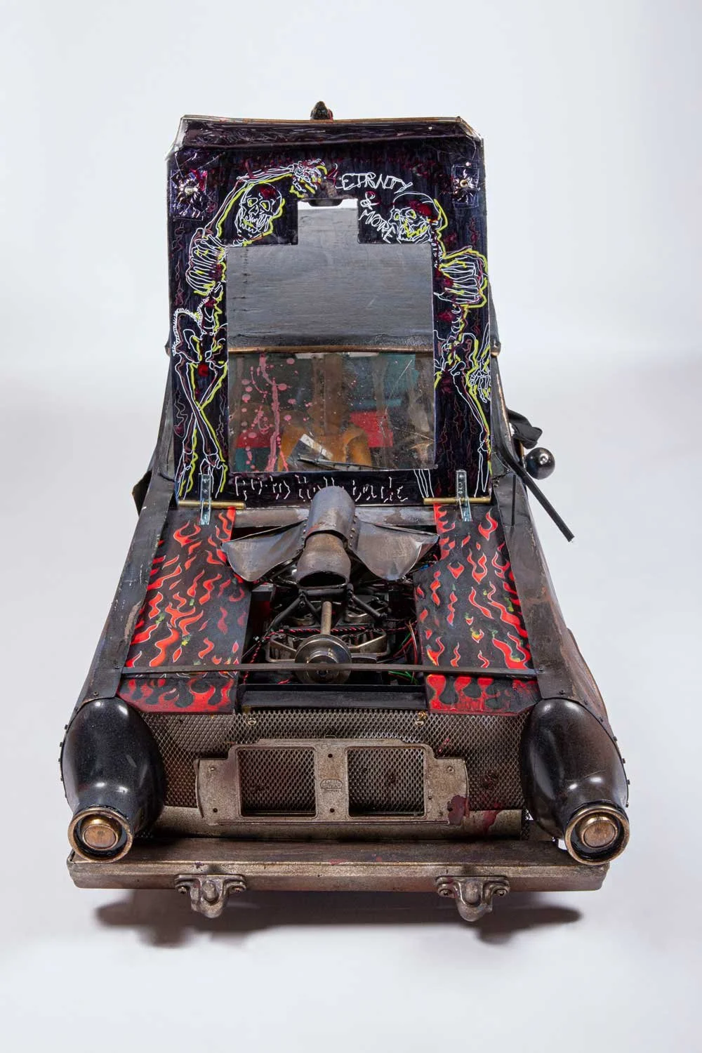 A vintage pinball machine with skeleton artwork and flames design on the playfield, featuring a glass top, metal components, and a black jump rope on the right side.