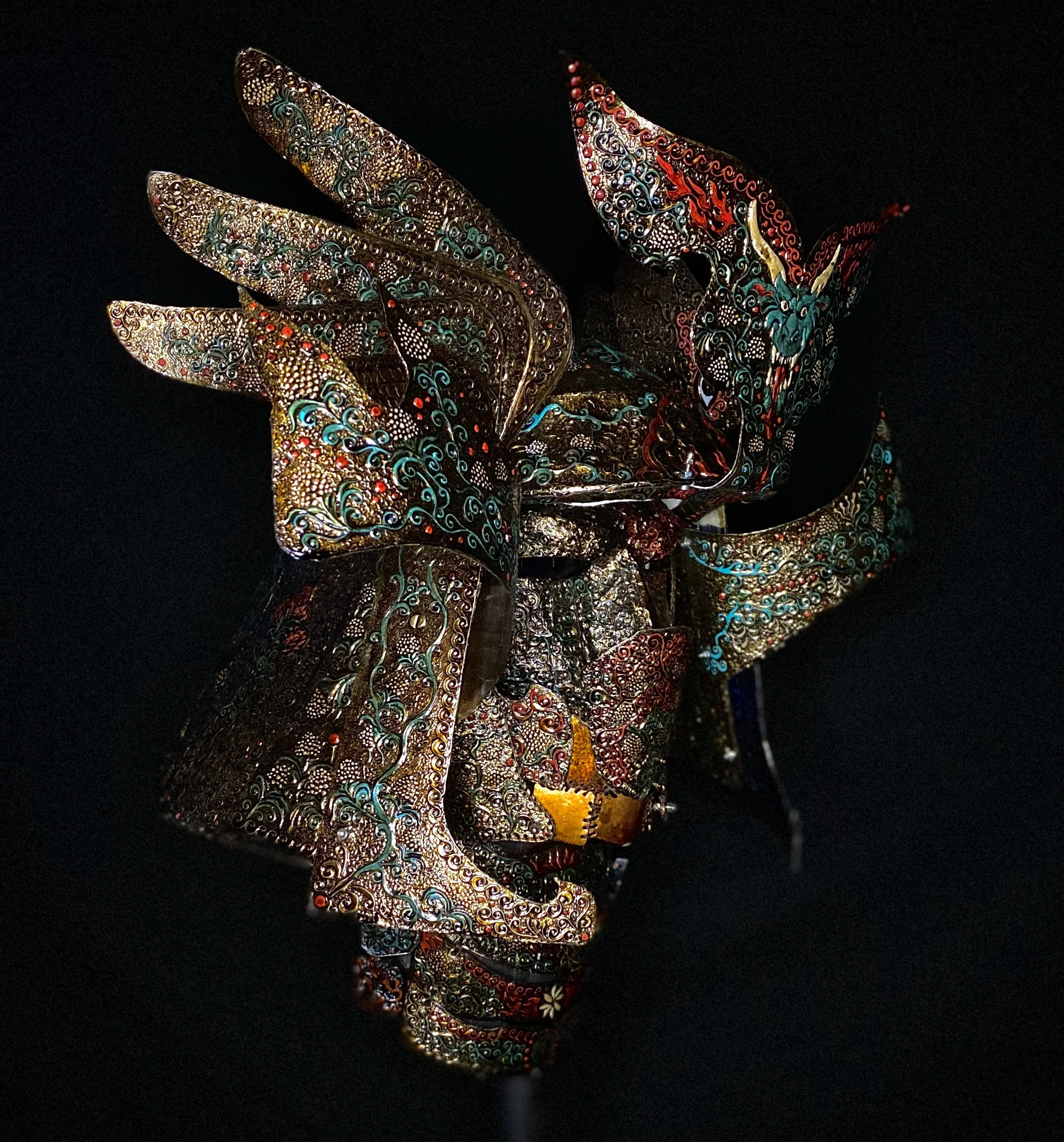 Decorative dragon warrior mask with intricate patterns and bright colors on a black background.