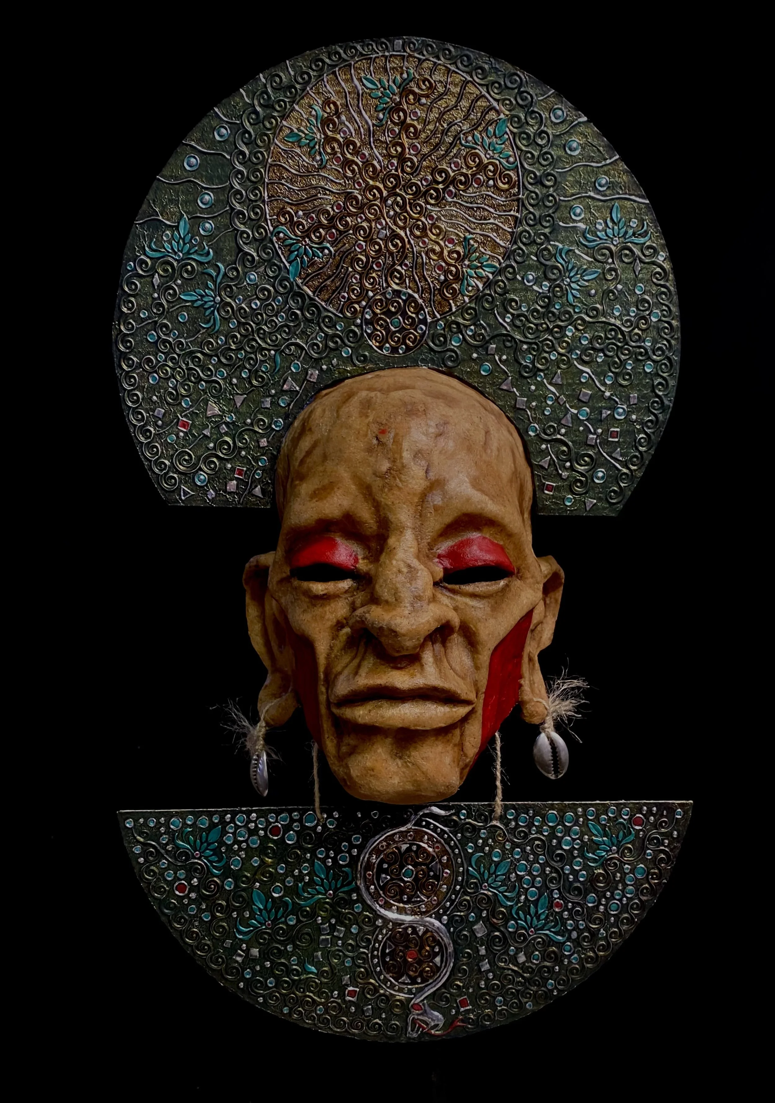 An art piece featuring a realistic person’s face with closed eyes, wearing makeup, earrings, and looking peaceful. Behind and above the face are intricate, circular metallic designs with colorful details, including a spiral and floral patterns, set against a black background.