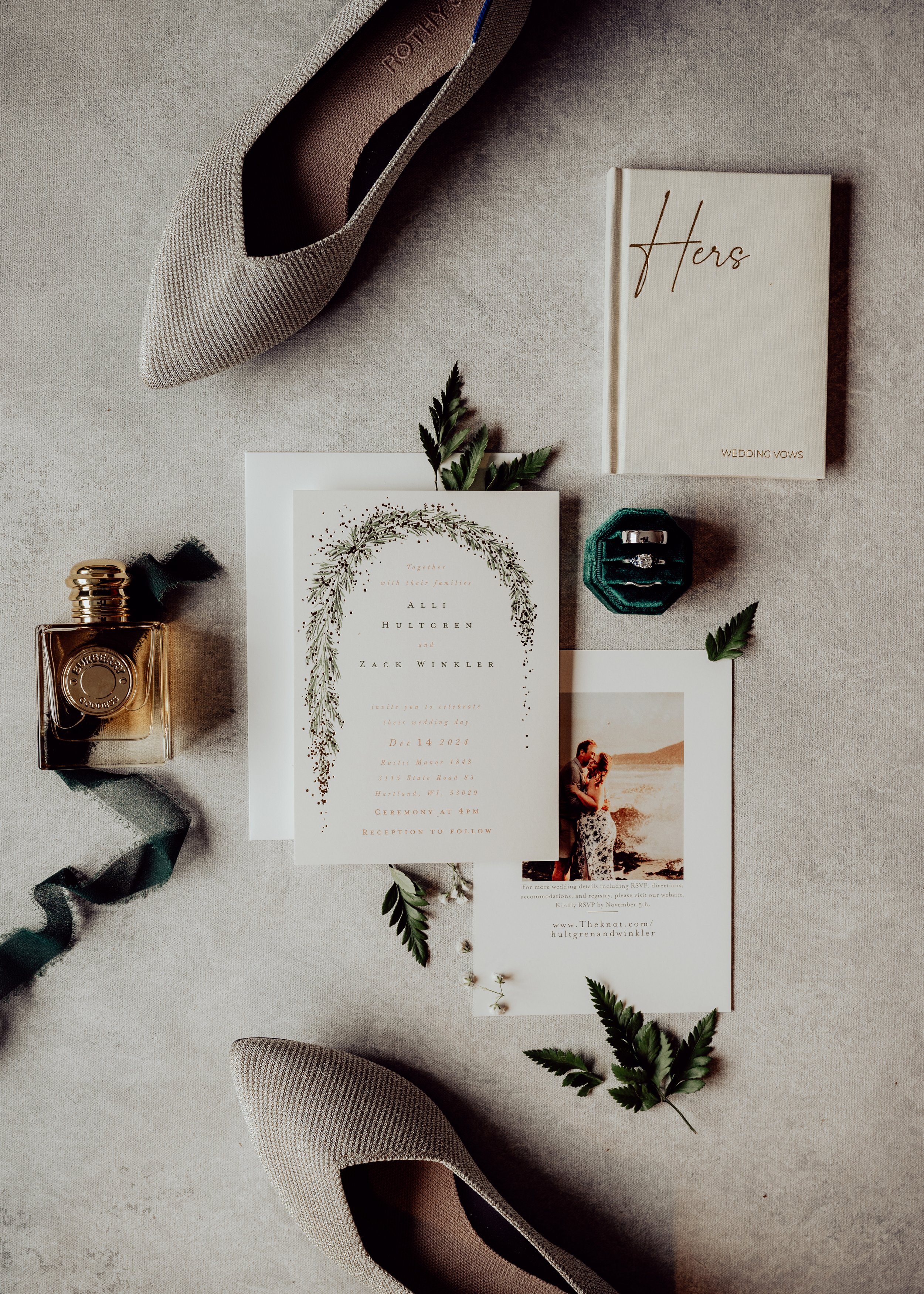 Wedding flat lays, Wedding invitation cards, a perfume bottle, greenery, a pair of shoes, and decorative ribbons placed on a neutral fabric surface. | Best Hawaii Wedding Photographer & Videographer | Oahu, Hawaii Island, Kauai, and Maui 