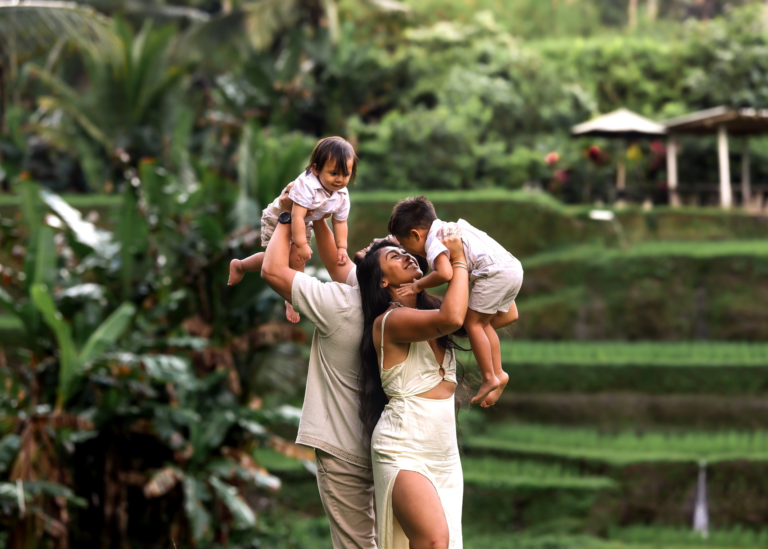A photo of an O'ahu family in Bali, Indonesia. A mom and dad holding their young children up smiling at them. | Wedding and Elopement Photography & Videography | Oahu, Kauai, Maui, Hawaii Island, Hawaii
