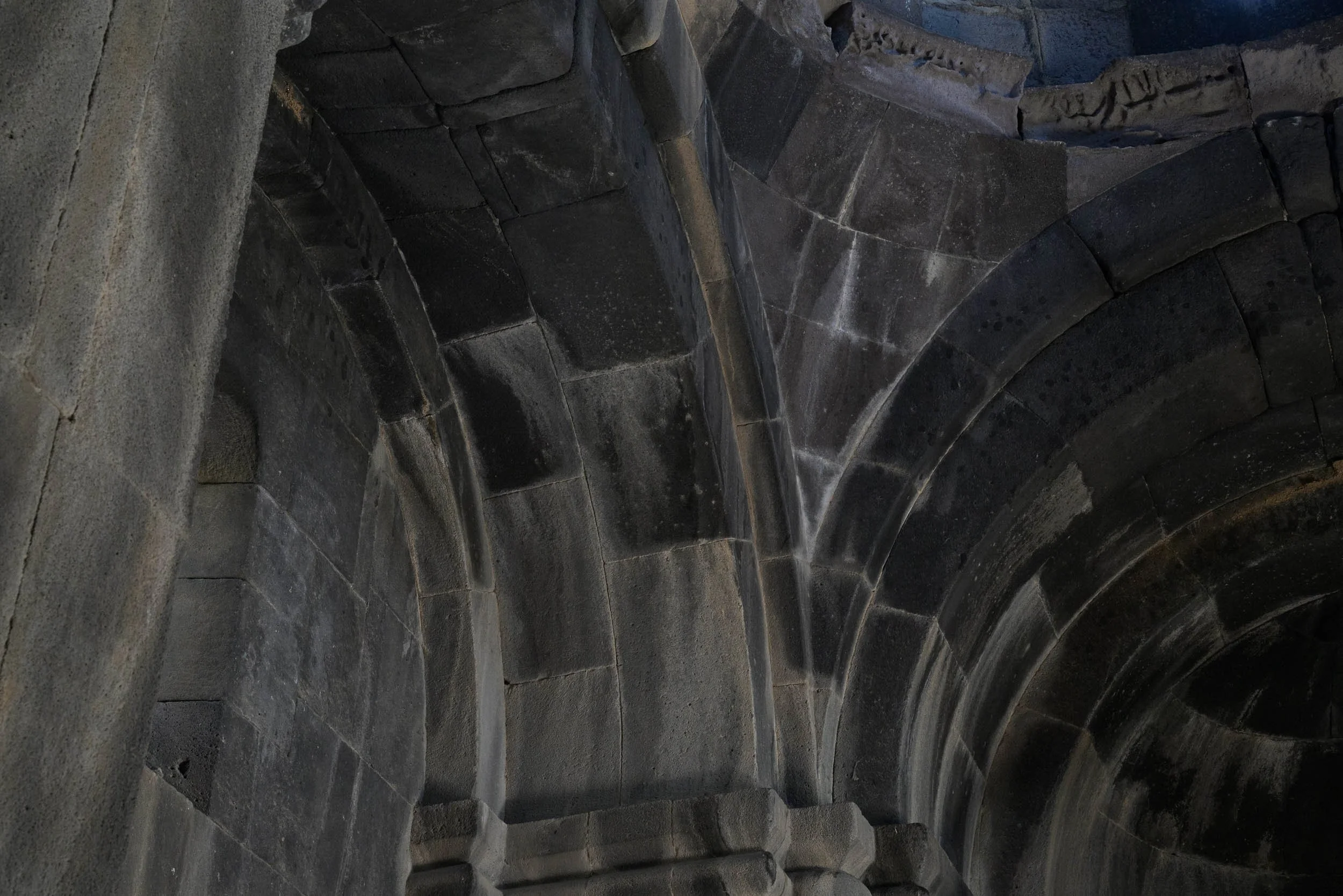 Dark stone vaulting and arches inside a medieval Armenian monastery.