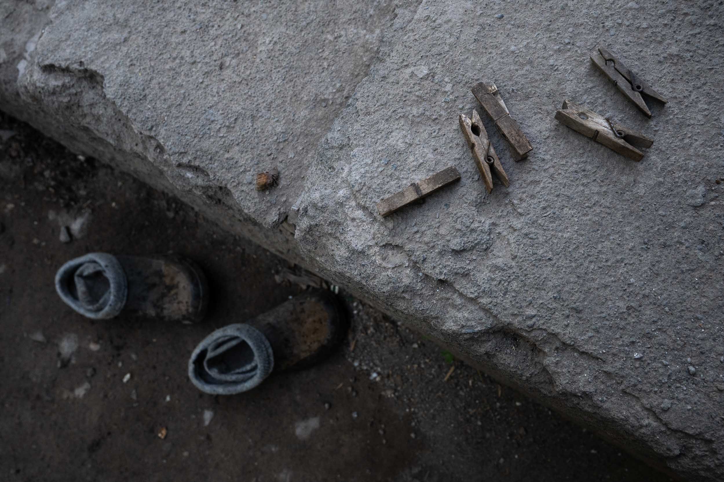 Close-up view of construction tools and supplies on a concrete surface, including metal clips, pipes, and a rolled-up piece of fabric or and other building materials.