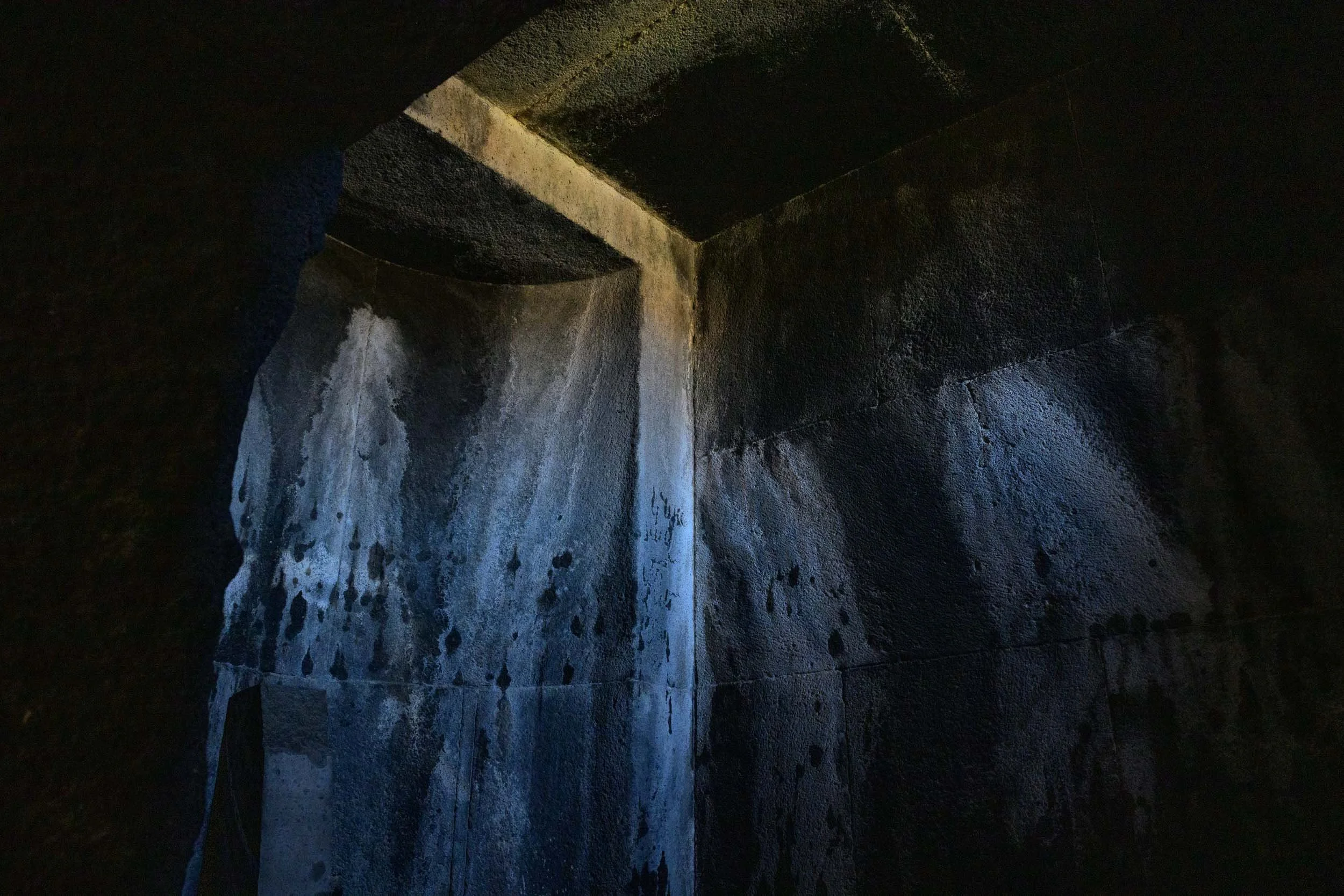Shaft of light illuminating weathered stone inside a dark medieval Armenian monastery.