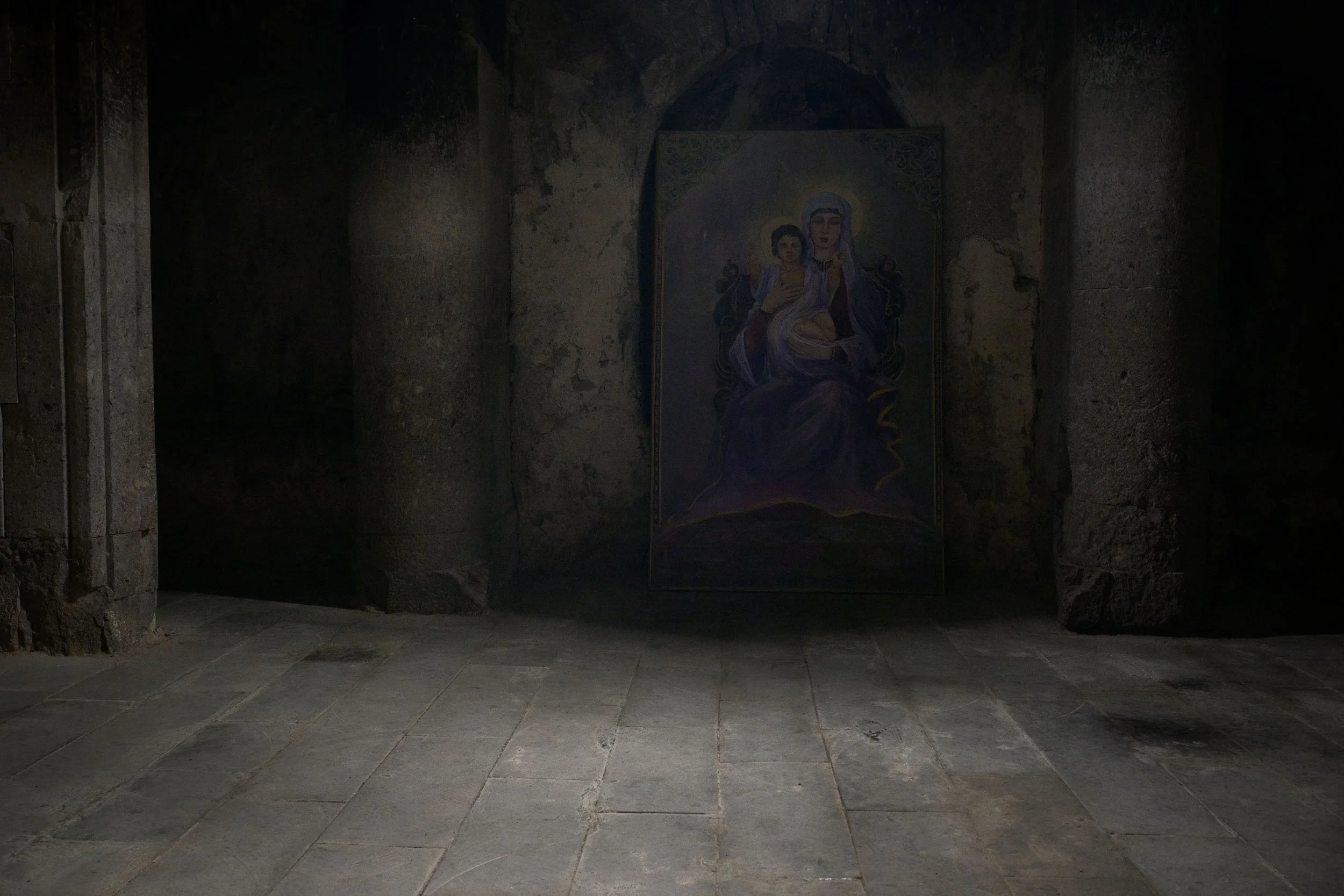 Icon of the Virgin and Child illuminated in a shaft of light inside an Armenian medieval monastery.