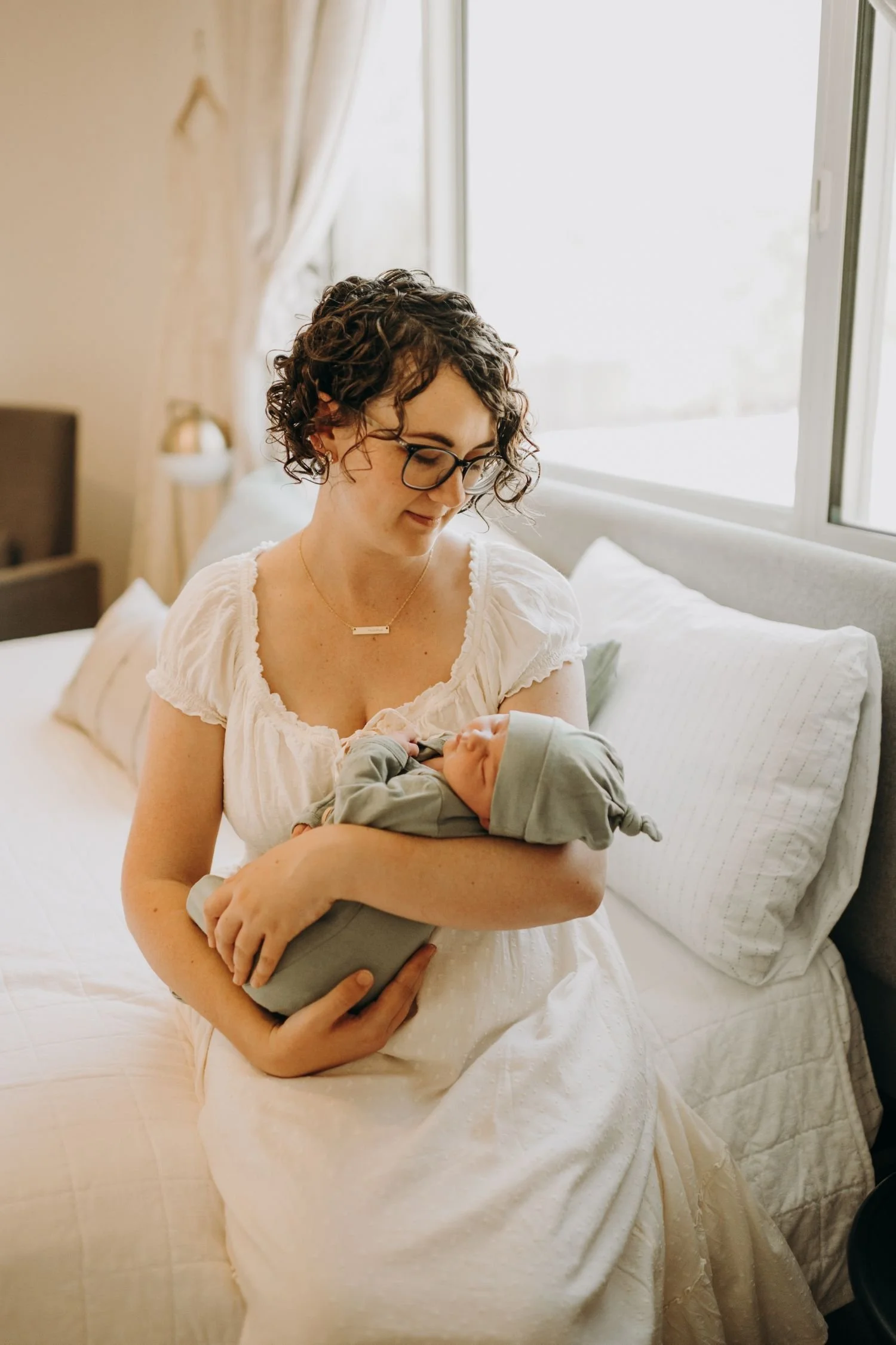 Jenna, at 2 weeks postpartum, looking lovingly at her newborn baby.