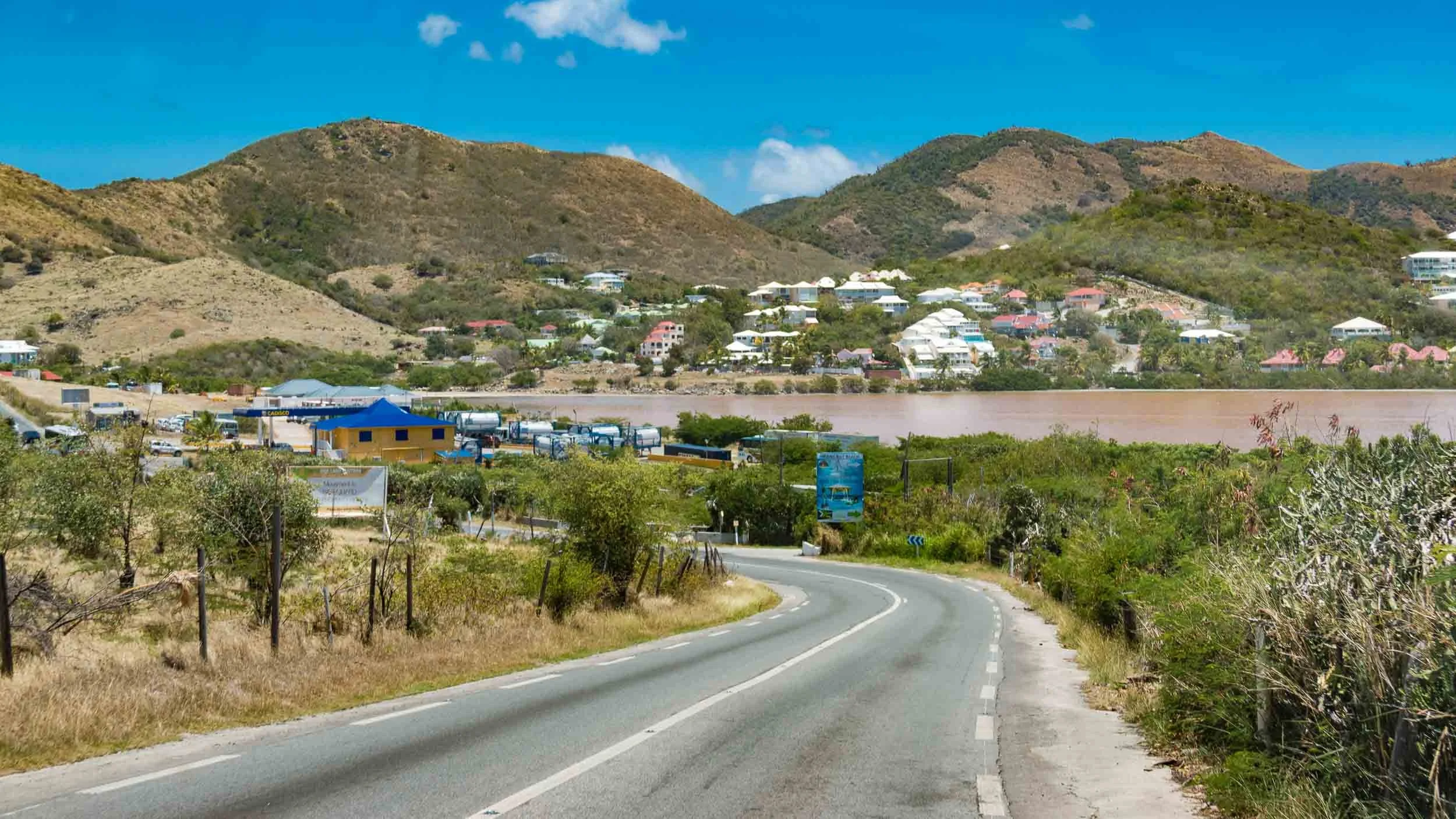 A driving view overlooking Étang Chevrise (Chevrise Pond) on the French side of Saint Martin, looking toward the hills of Mont Vernon and Cul-de-Sac. We are driving on  Route de l'Espérance (N7), the main road that winds through the northern part of 